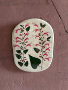 An oval ceramic tile with botanical black currant sage leaves pressed into cream-colored clay and air dried NC art