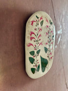 An oval ceramic tile with botanical black currant sage leaves pressed into cream-colored clay and air dried NC art