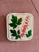 A square ceramic tile with botanical pressed bleeding heart flower stem and foliage on cream clay by NC artist