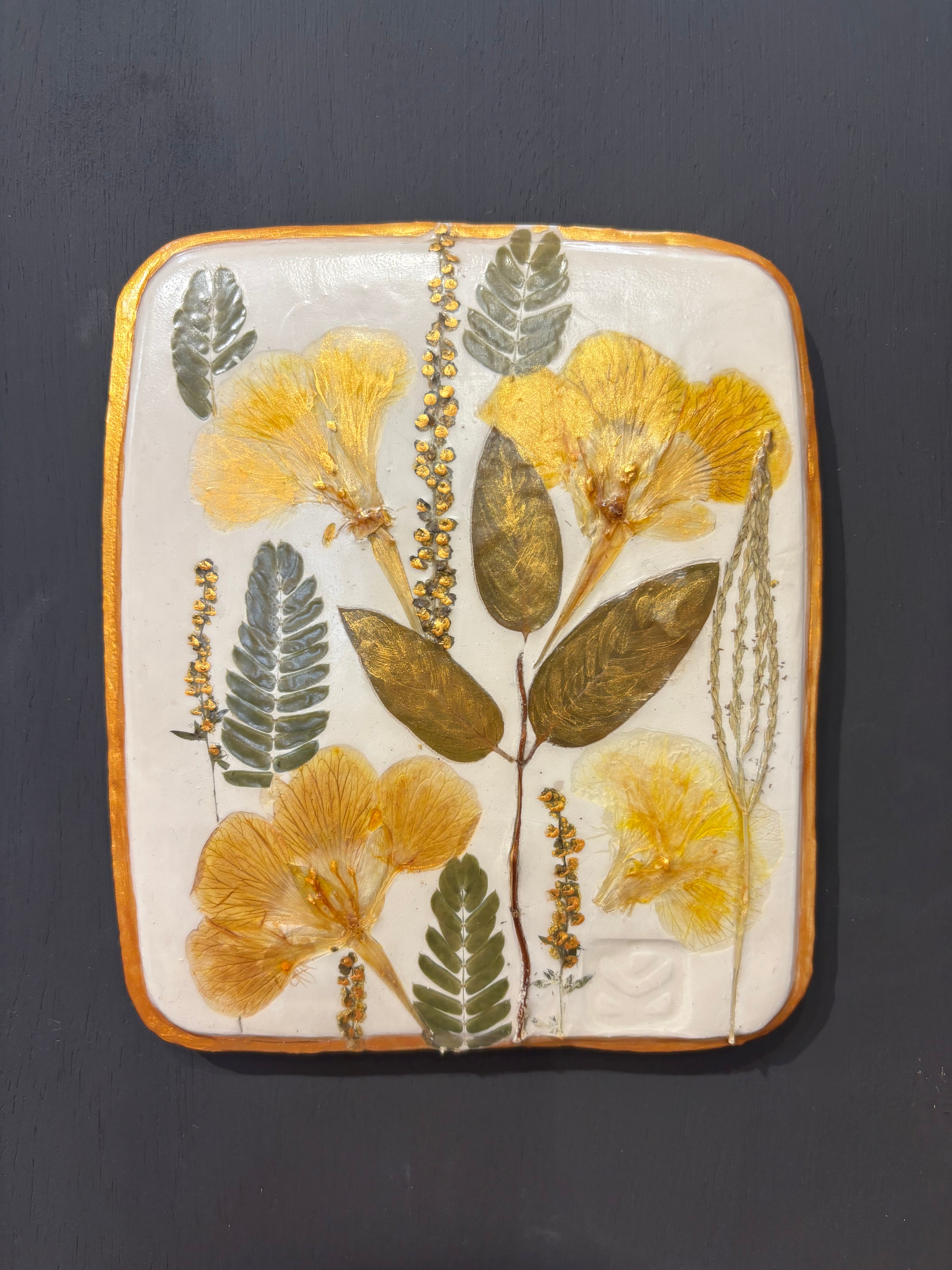 A square ceramic tile with botanical pressed wild evening yellow primrose and foliage on cream clay by NC artist