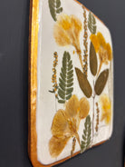 A square ceramic tile with botanical pressed wild evening yellow primrose and foliage on cream clay by NC artist