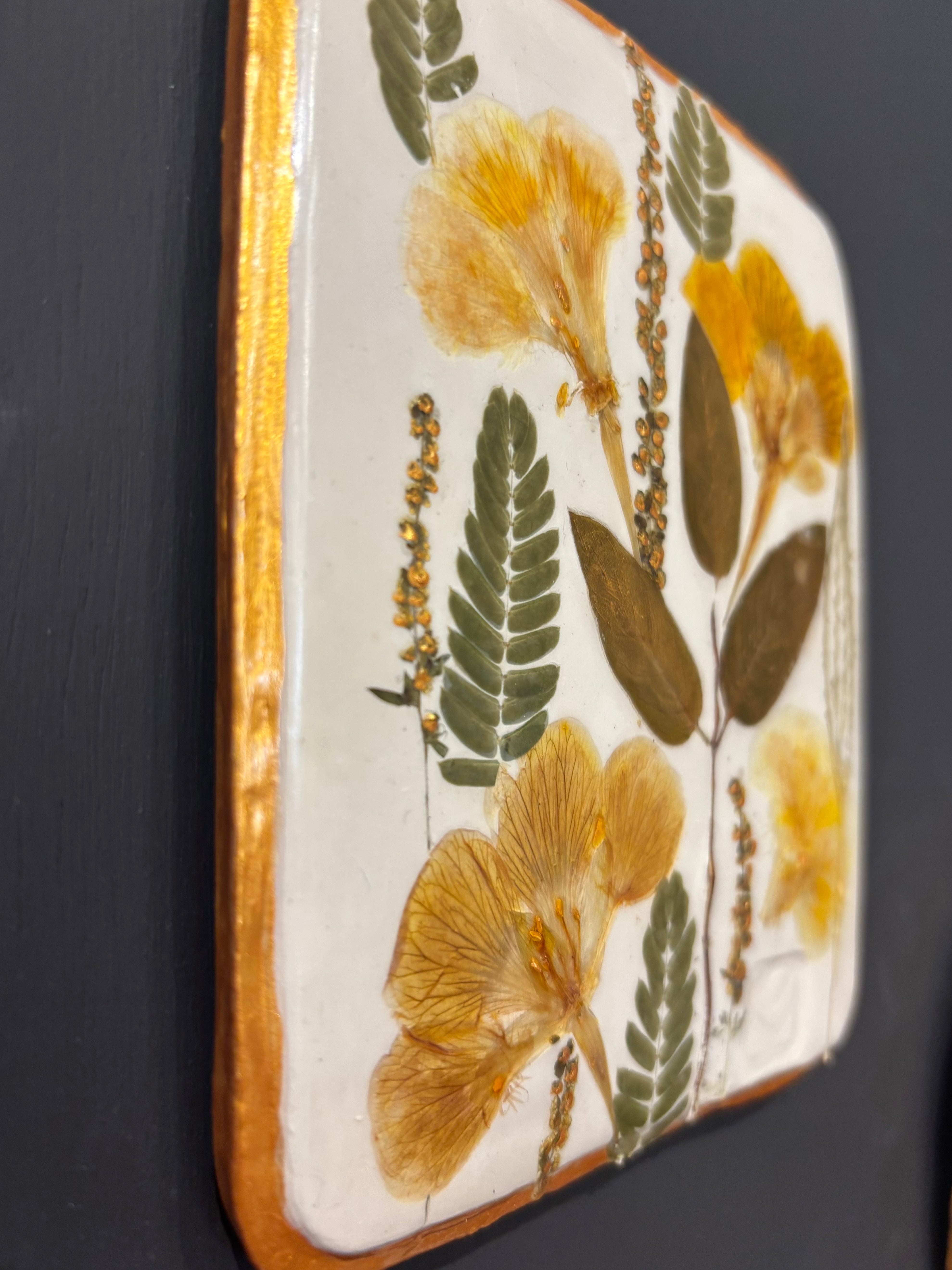 A square ceramic tile with botanical pressed wild evening yellow primrose and foliage on cream clay by NC artist