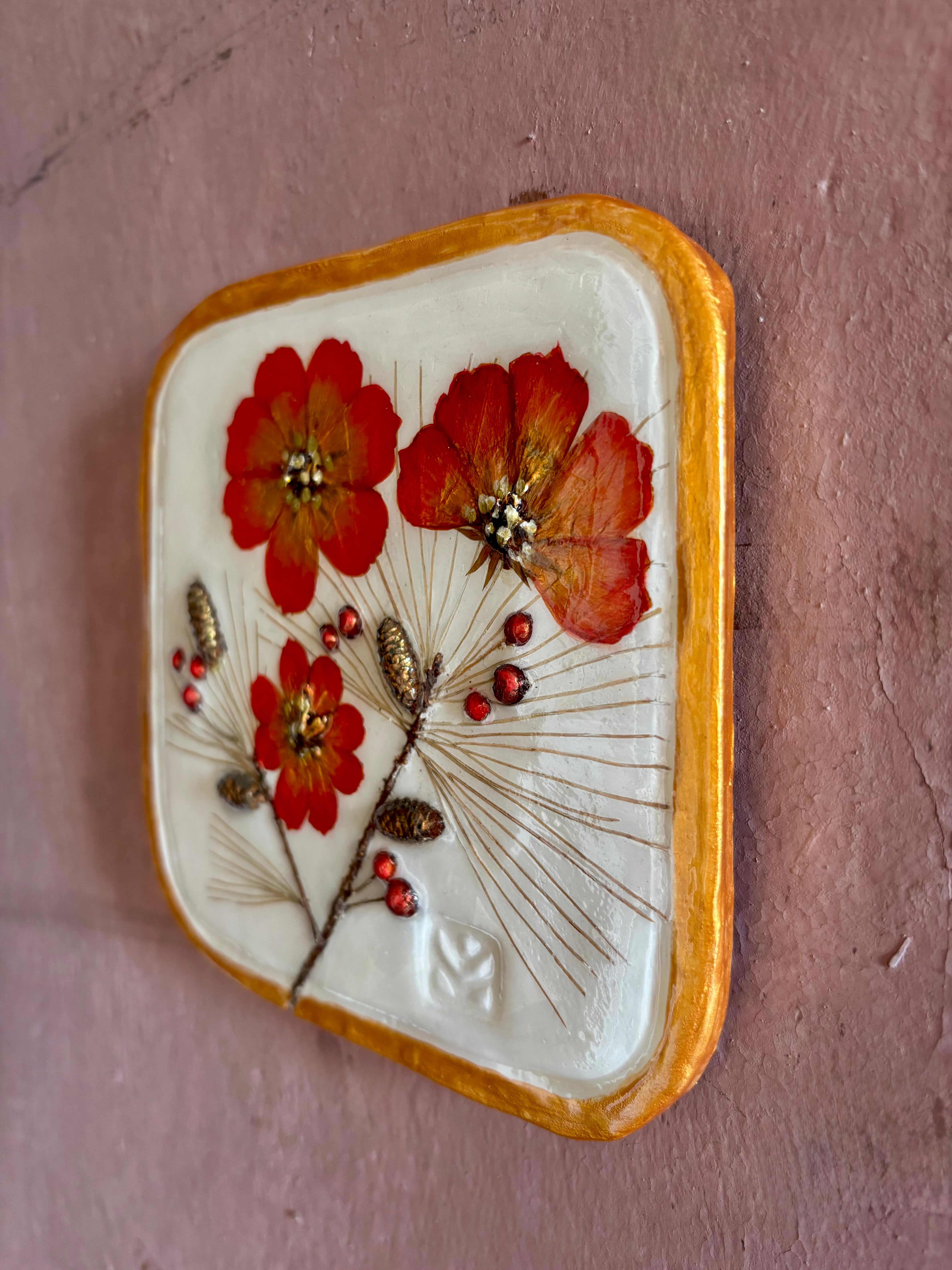 A square ceramic wall sculptural pressed botanical elements holly cosmos pine needles pinecones and red berries