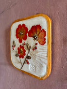 A square ceramic wall sculptural pressed botanical elements holly cosmos pine needles pinecones and red berries