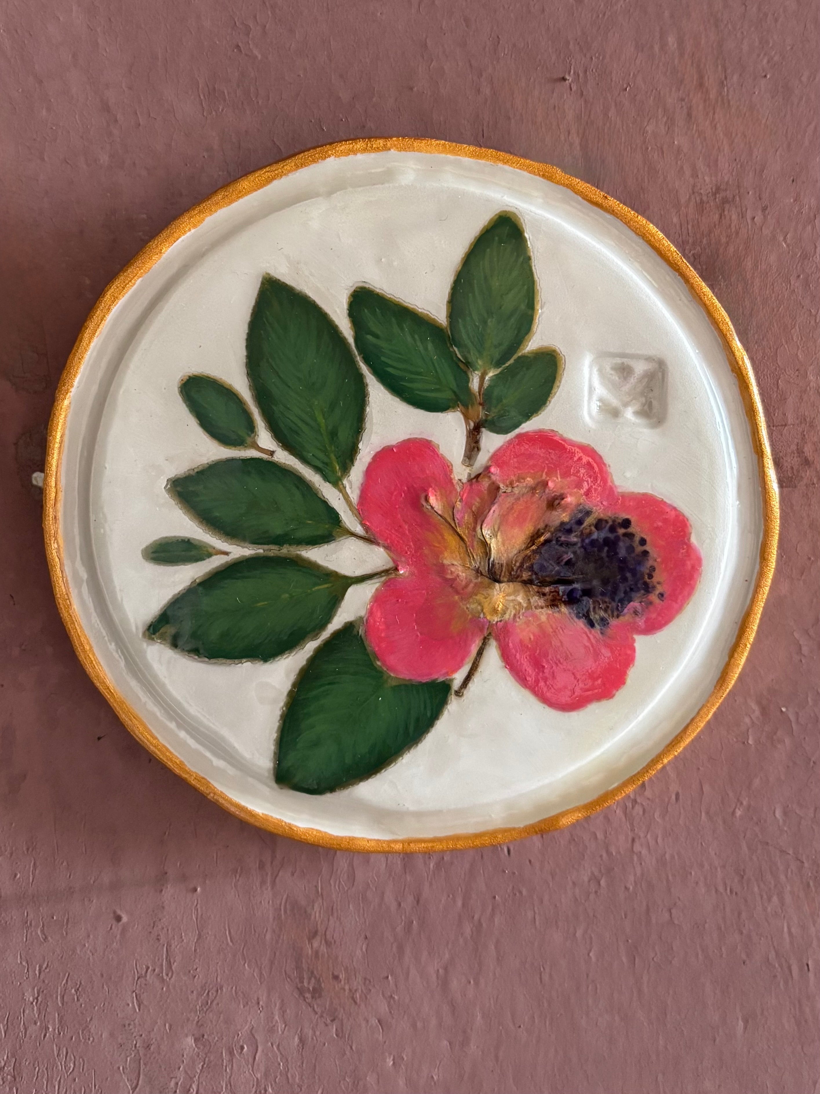 A round white ceramic tile with sappora rhododendron bloom botanical press green leaves and hand painted gold rim