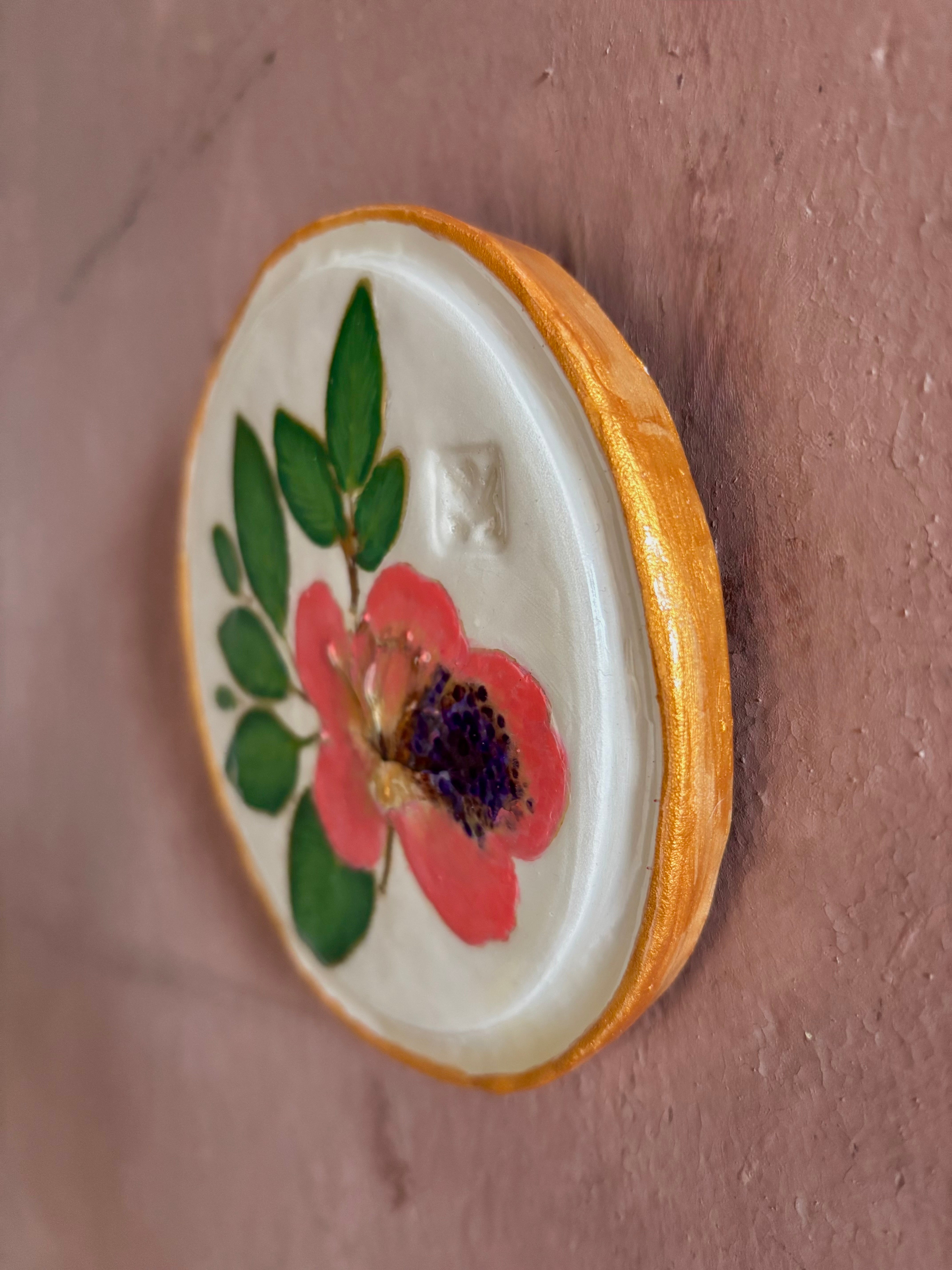A round white ceramic tile with sappora rhododendron bloom botanical press green leaves and hand painted gold rim