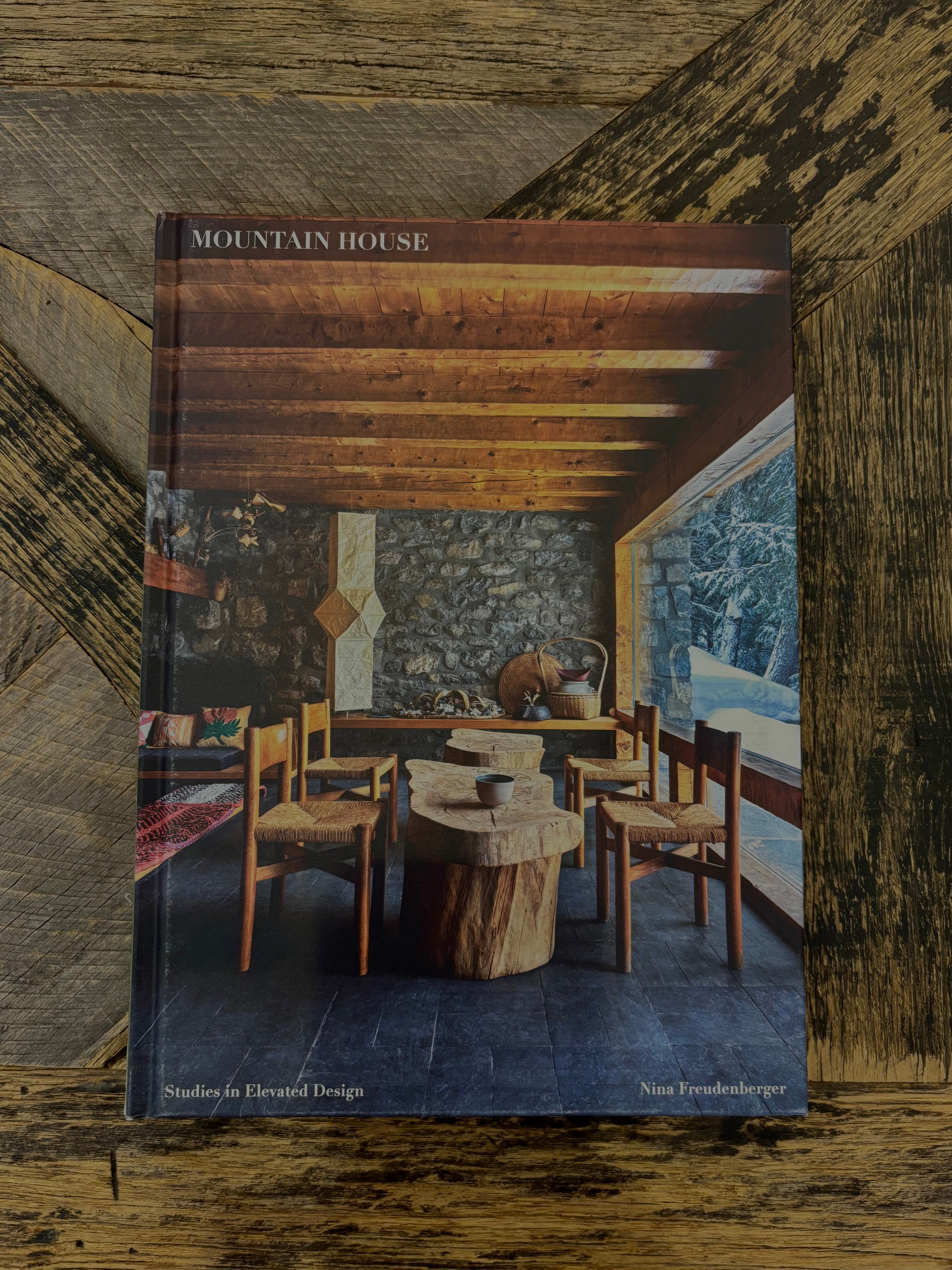 A hardcover book titled 'Mountain House: Studies in Elevated Design' by Nina Wyndenschuster, featuring a rustic interior dining room cover