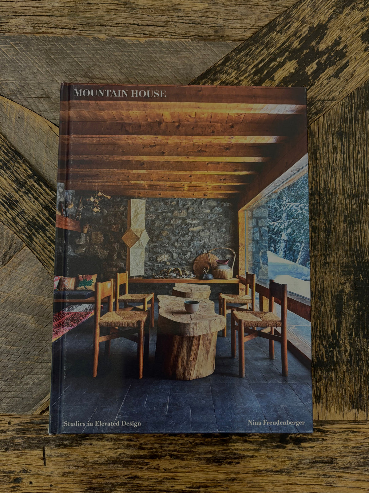 A hardcover book titled 'Mountain House: Studies in Elevated Design' by Nina Wyndenschuster, featuring a rustic interior dining room cover