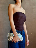 Woman wearing the Italian leather Mini Cloud crossbody by high-end designer Mansur Gavriel in metallic silver with removeable shoulder strap that can also double as a clutch