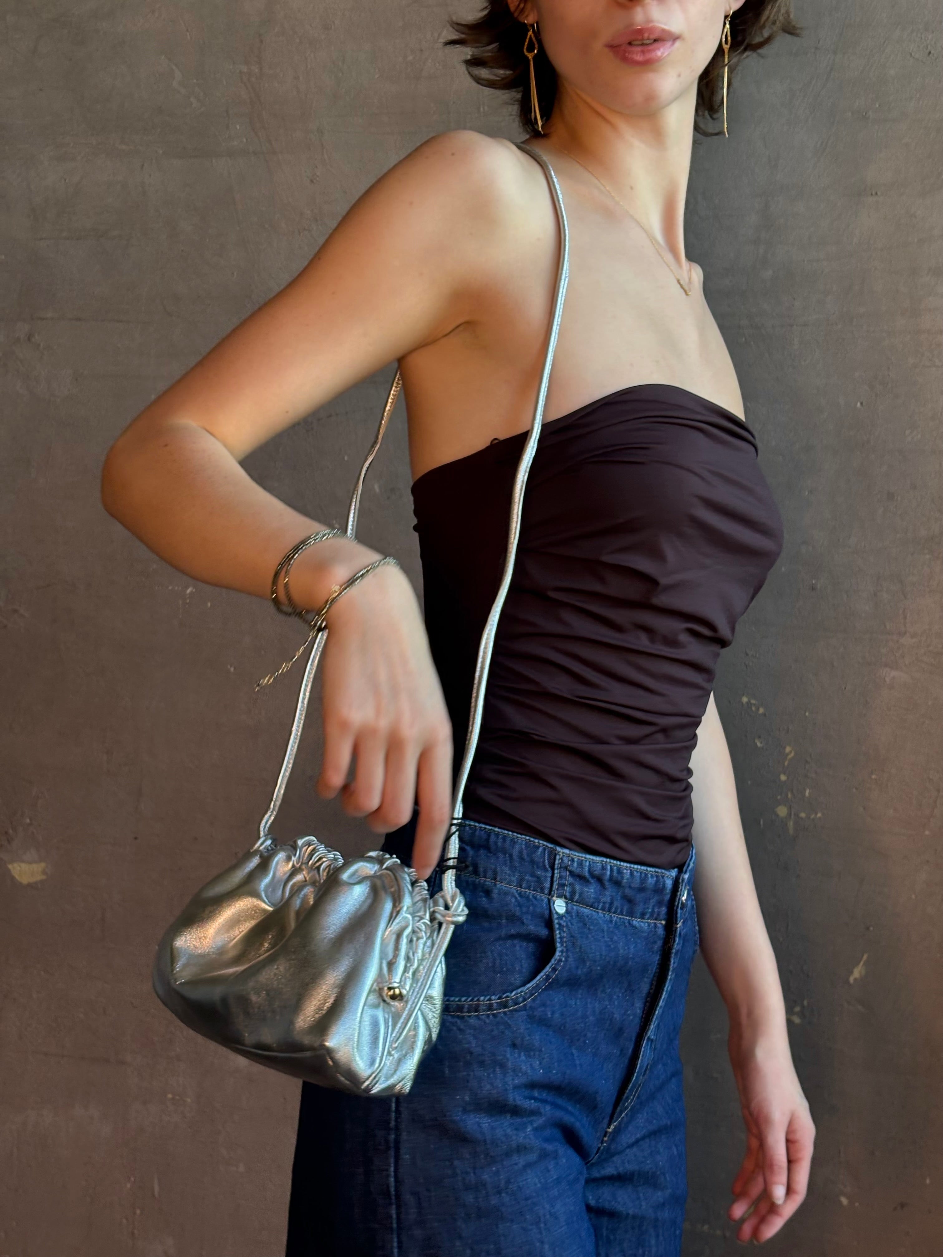Woman wearing the Italian leather Mini Cloud crossbody by high-end designer Mansur Gavriel in metallic silver with removeable shoulder strap that can also double as a clutch