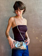 Woman wearing the Italian leather Mini Cloud crossbody by high-end designer Mansur Gavriel in metallic silver with removeable shoulder strap that can also double as a clutch