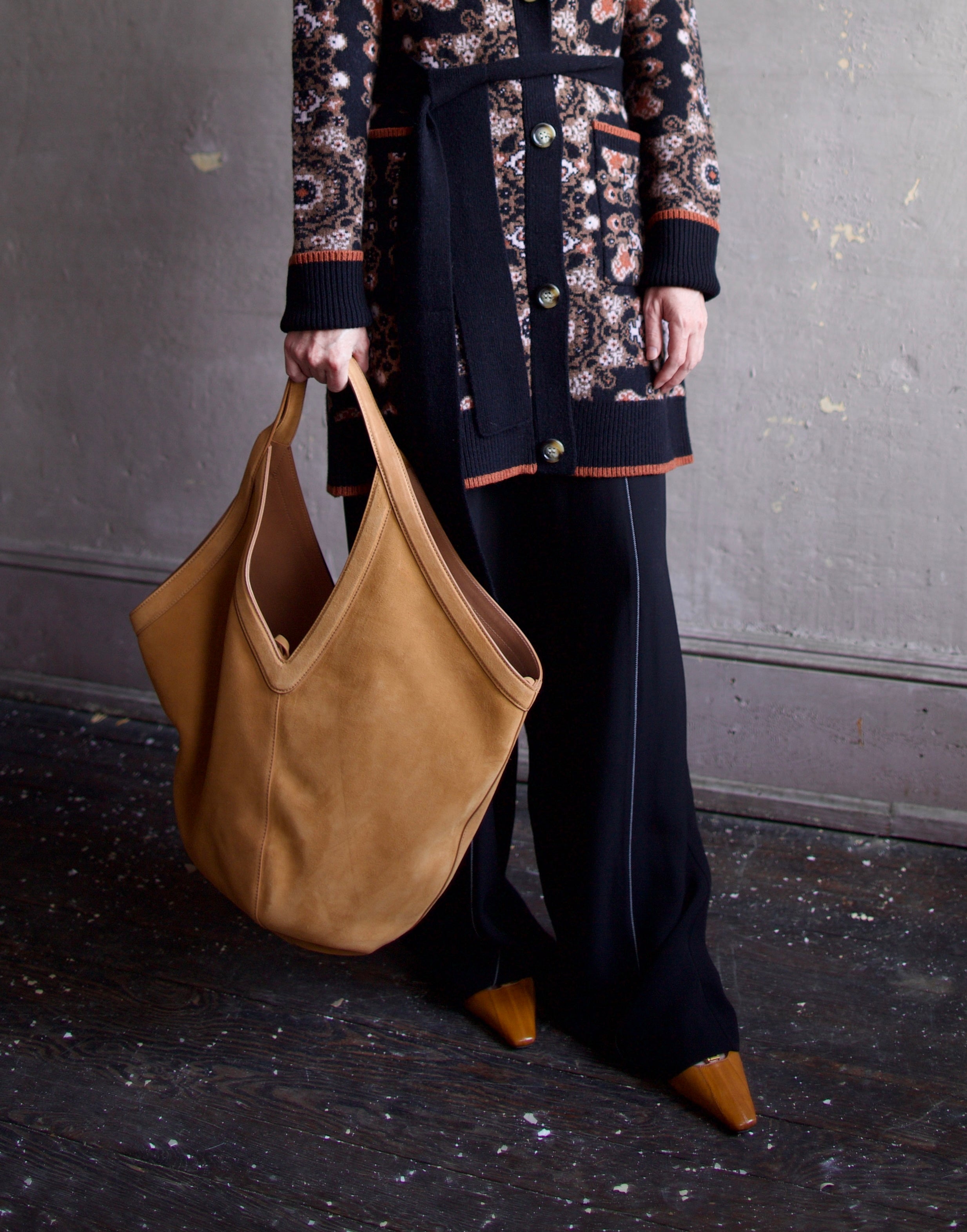 Image featuring a woman holding the Mansur Gavriel soft hobo with a double tie closure, oversized and a shoulder handle with v-detail in light brown suede leather.