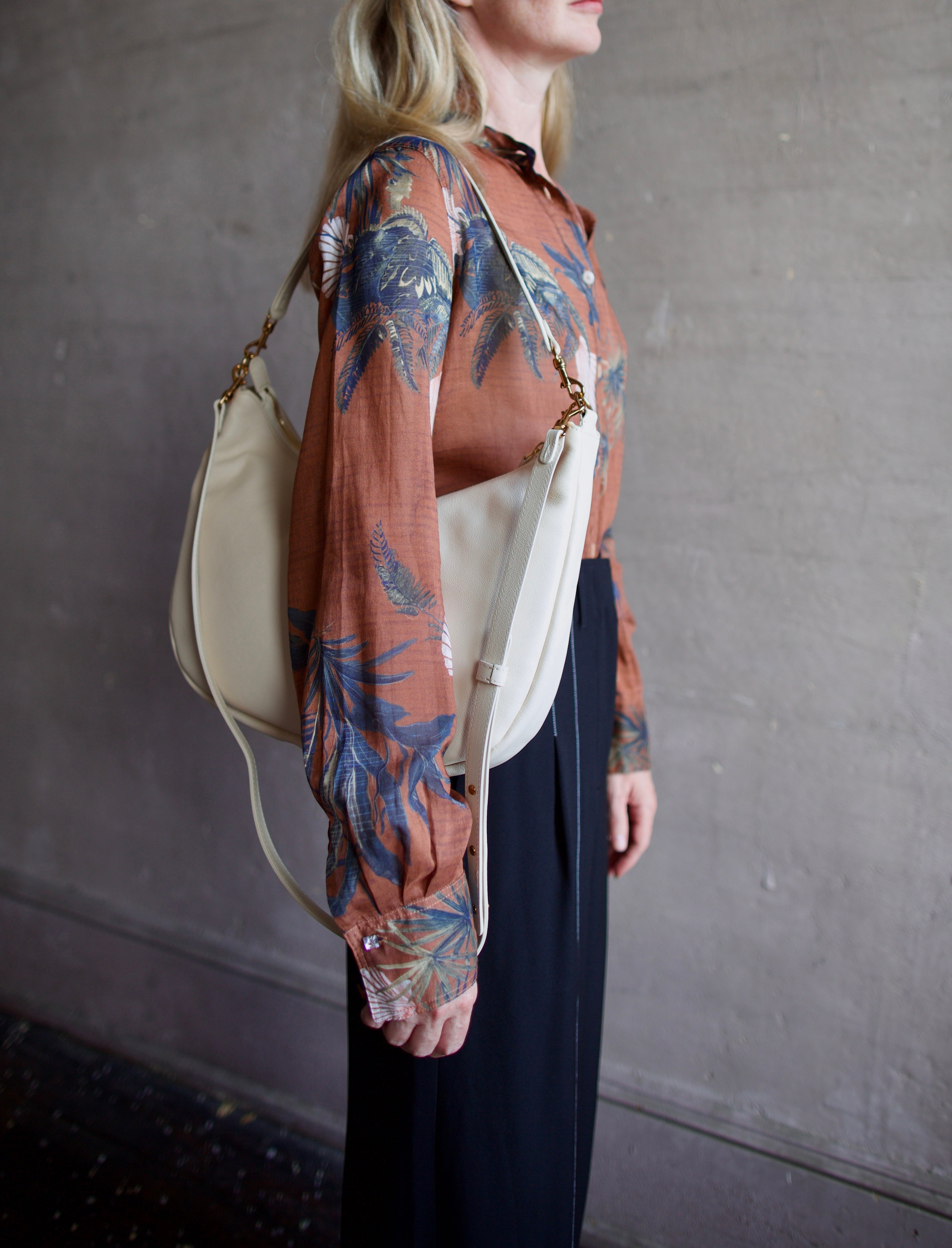 Mature model wearing the Swing Bag by High-end designer Mansur Gavriel in cream color with gold finish hardware