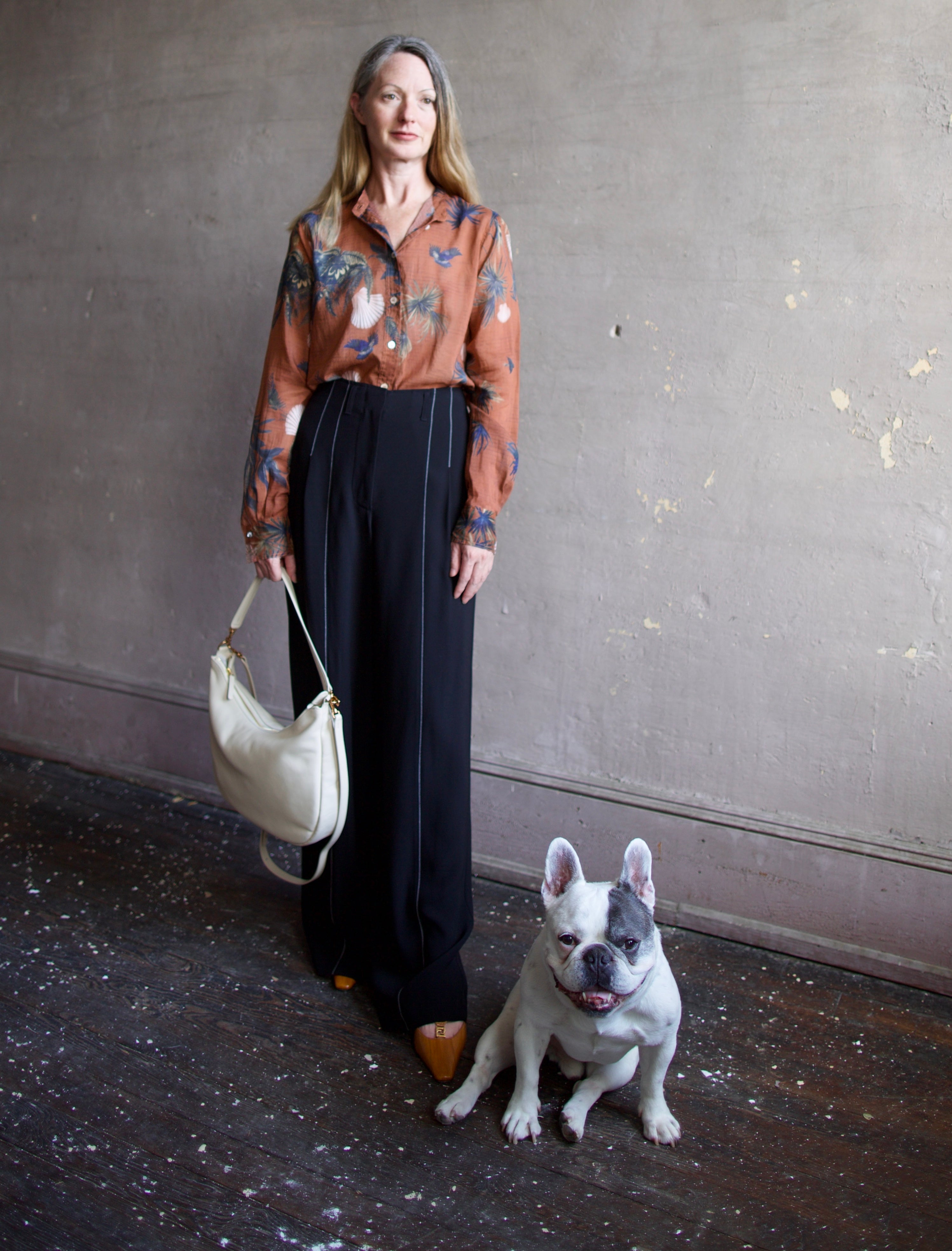 French bulldog and mature model wearing the Swing Bag by High-end designer Mansur Gavriel in cream color with gold finish hardware