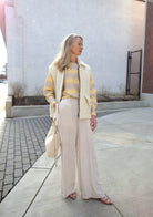 Mature woman holding Mansur Gavriel Swing leather bag in Ivory a warm winter white with two optional leather straps for a versitale handbag ready for any adventure