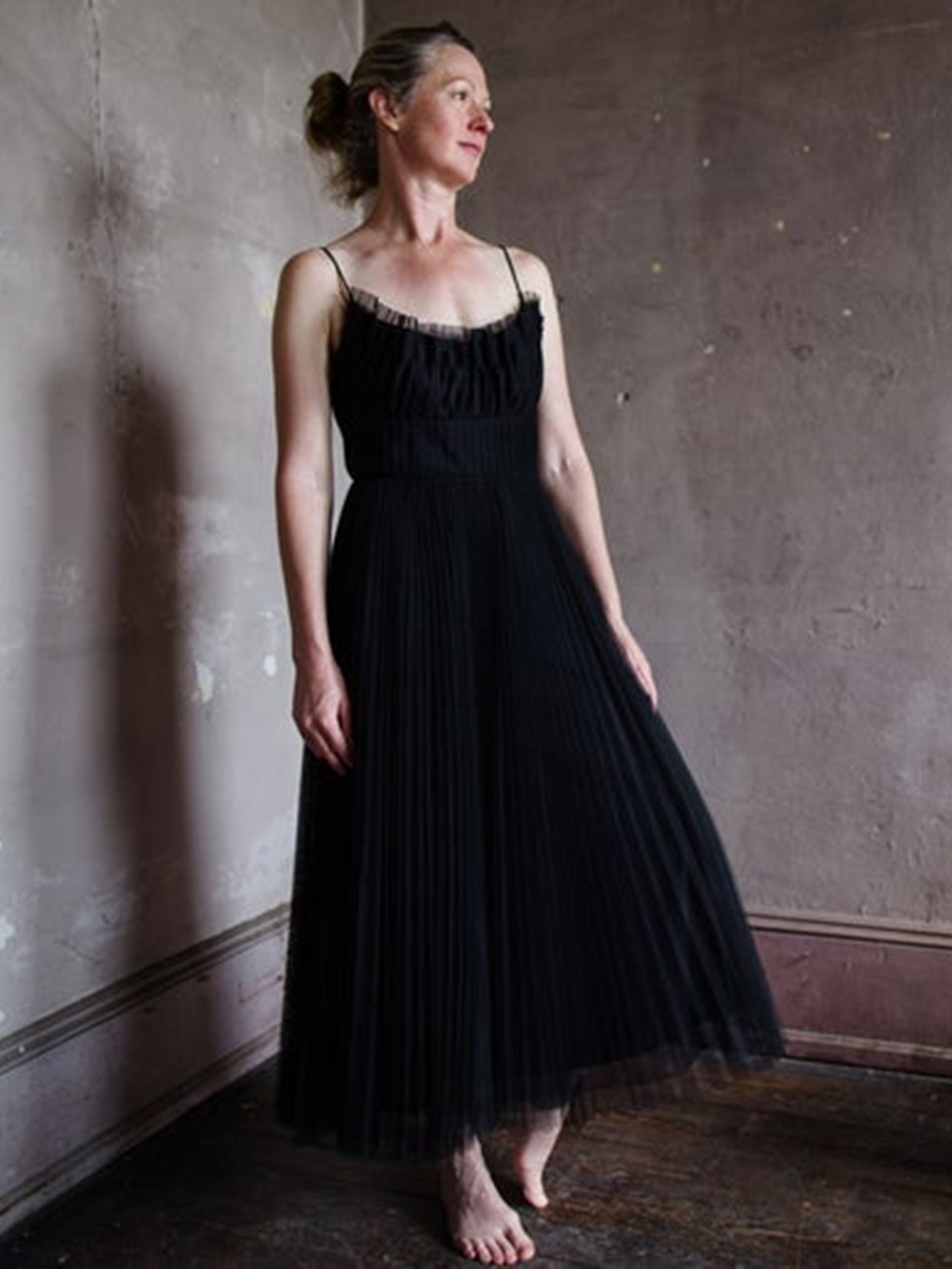 Image featuring a woman wearing the pleated tulle classic dress by Monique Lhuillier with spaghetti straps, a tailored bodice and pleated ankle hem in black.