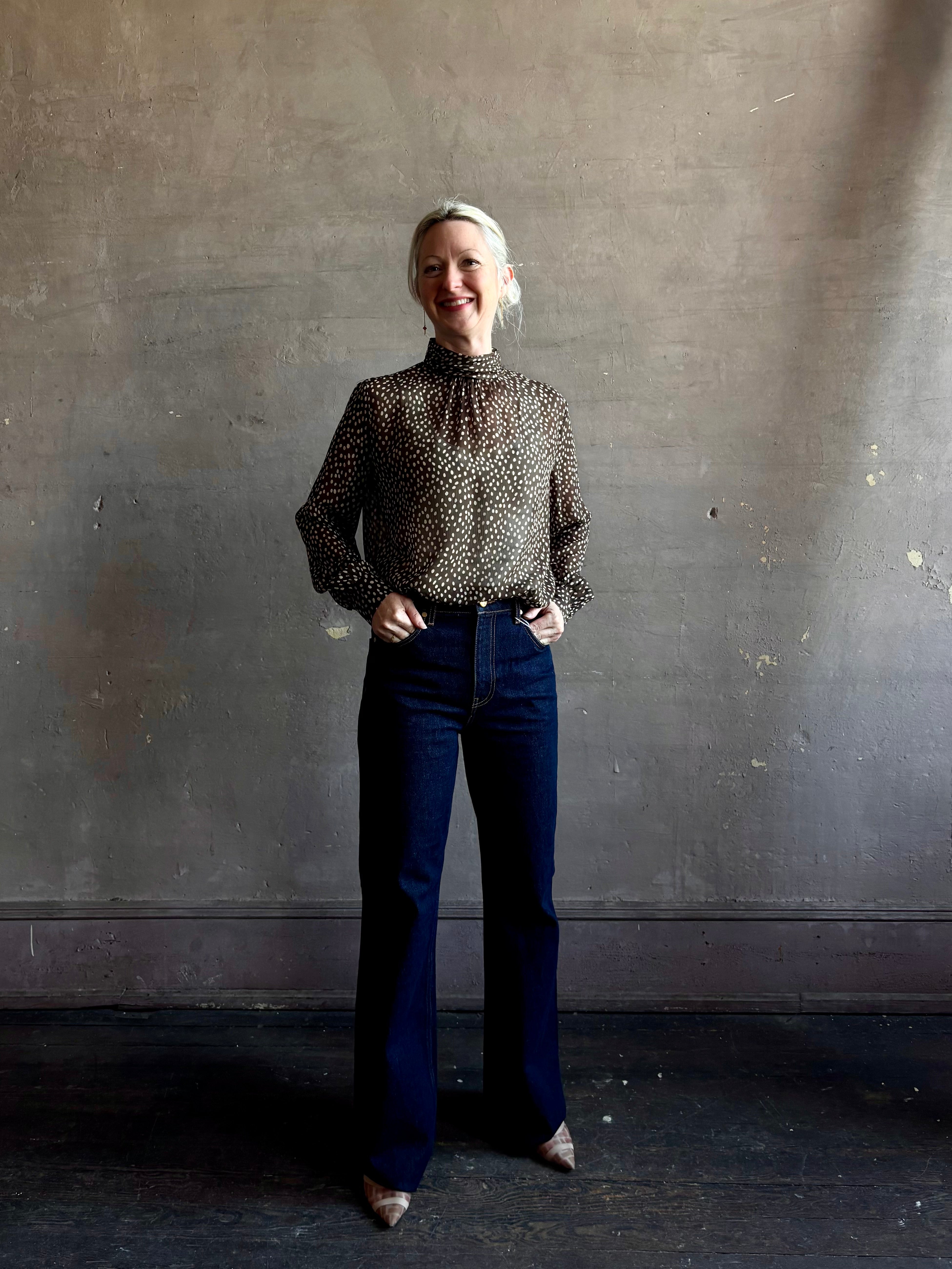 Mature woman wearing Nili Lotan Silk Demie Blouse in Brown/Cream Wild Dots sheer mock neck and keyhole back closure. Made in the USA