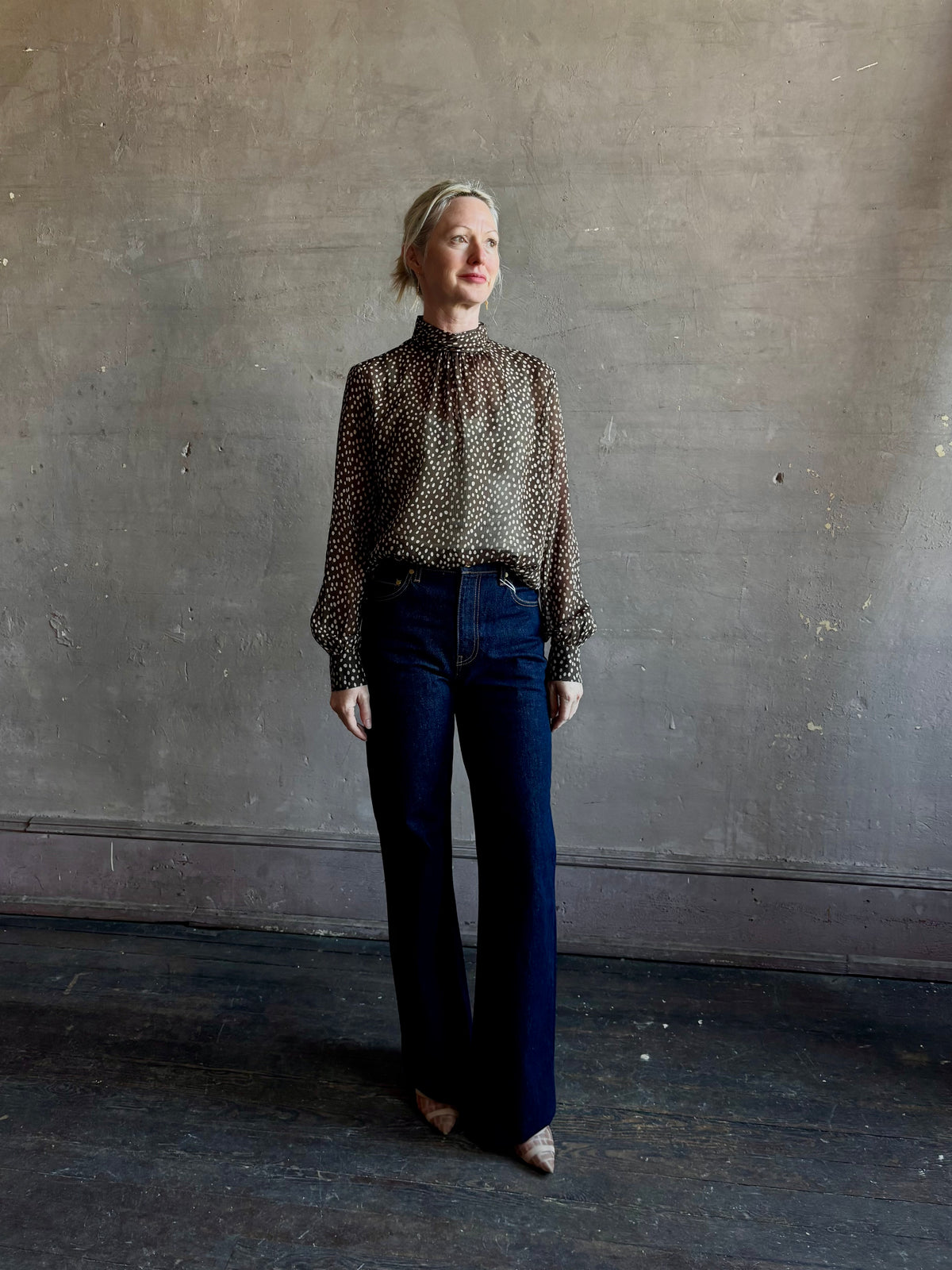 Mature woman wearing Nili Lotan Silk Demie Blouse in Brown/Cream Wild Dots sheer mock neck and keyhole back closure. Made in the USA