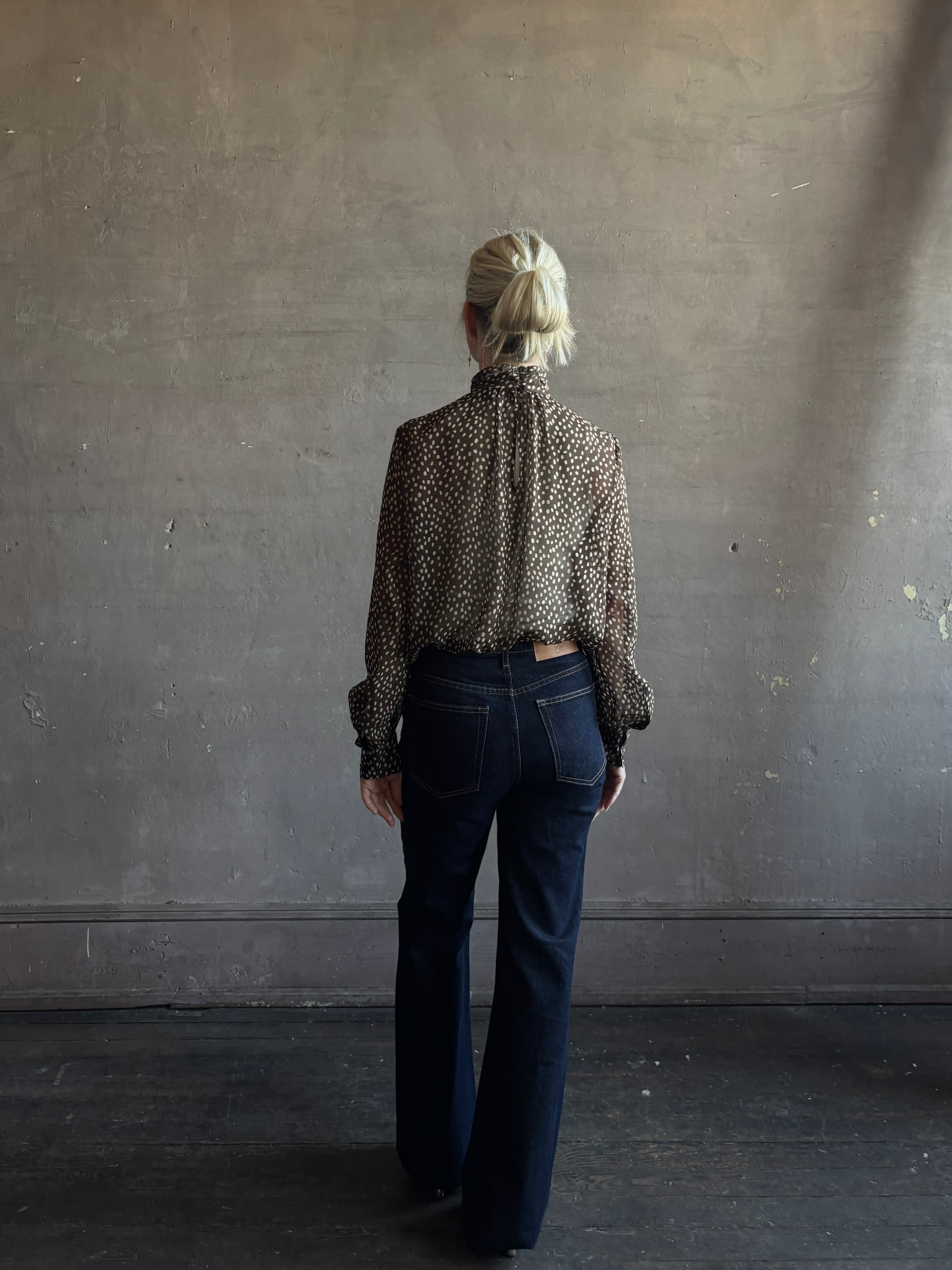 Mature woman wearing Nili Lotan Silk Demie Blouse in Brown/Cream Wild Dots sheer mock neck and keyhole back closure. Made in the USA