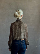 Mature woman wearing Nili Lotan Silk Demie Blouse in Brown/Cream Wild Dots sheer mock neck and keyhole back closure. Made in the USA