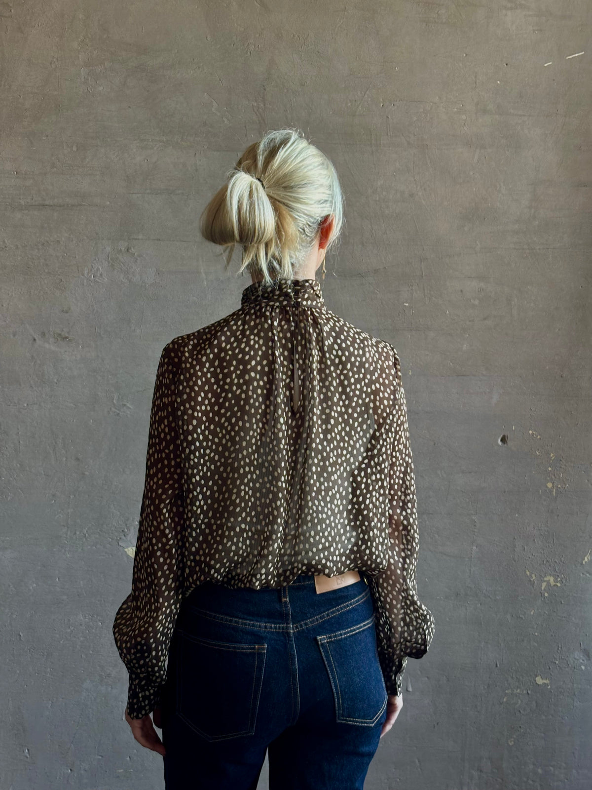 Mature woman wearing Nili Lotan Silk Demie Blouse in Brown/Cream Wild Dots sheer mock neck and keyhole back closure. Made in the USA