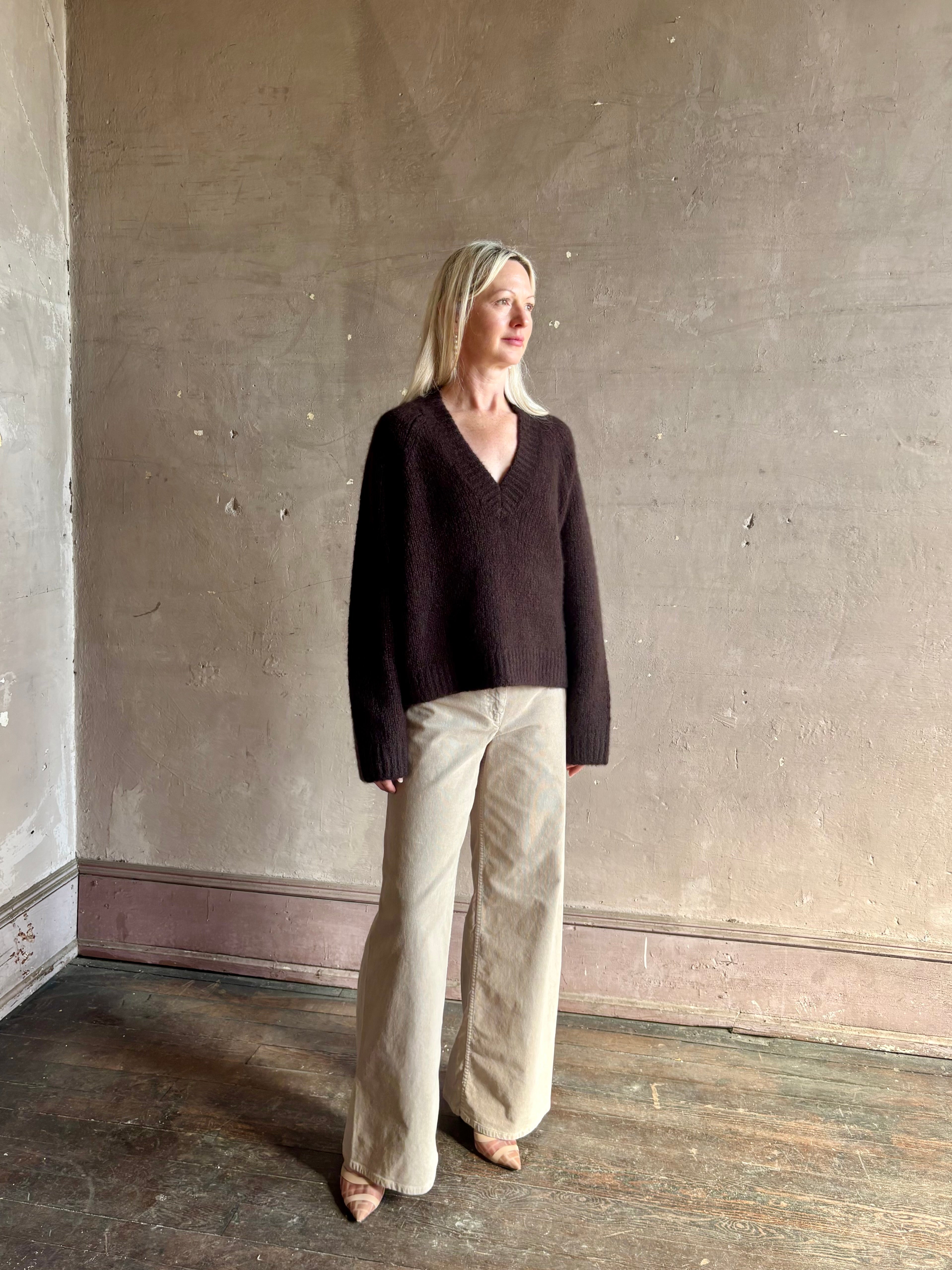 Mature woman wearing Nili Lotan's Isley Sweater Dark brown cashmere-silk  relaxed V-neck silhouette. Ultra-luxe
