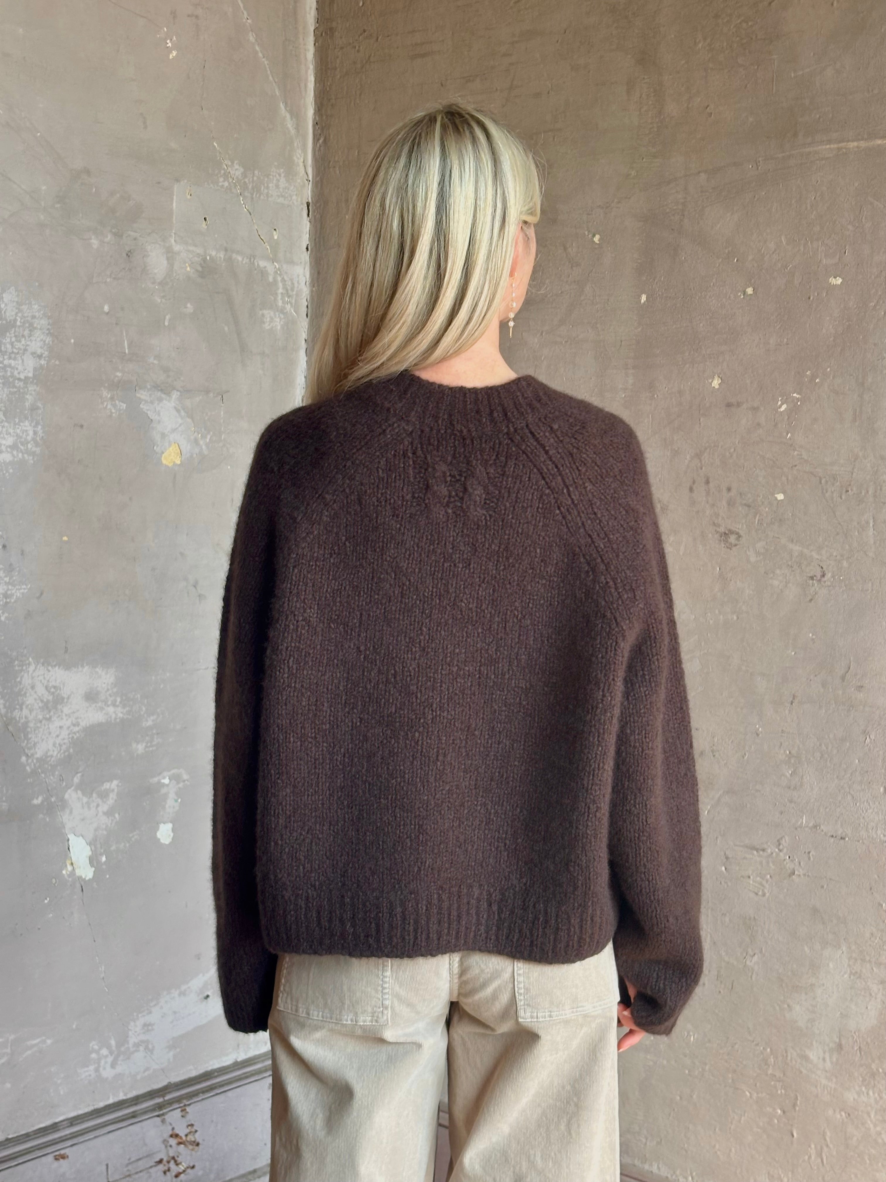 Mature woman wearing Nili Lotan's Isley Sweater Dark brown cashmere-silk  relaxed V-neck silhouette. Ultra-luxe