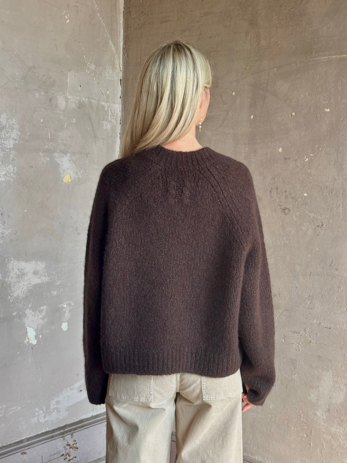 Mature woman wearing Nili Lotan's Isley Sweater Dark brown cashmere-silk  relaxed V-neck silhouette. Ultra-luxe