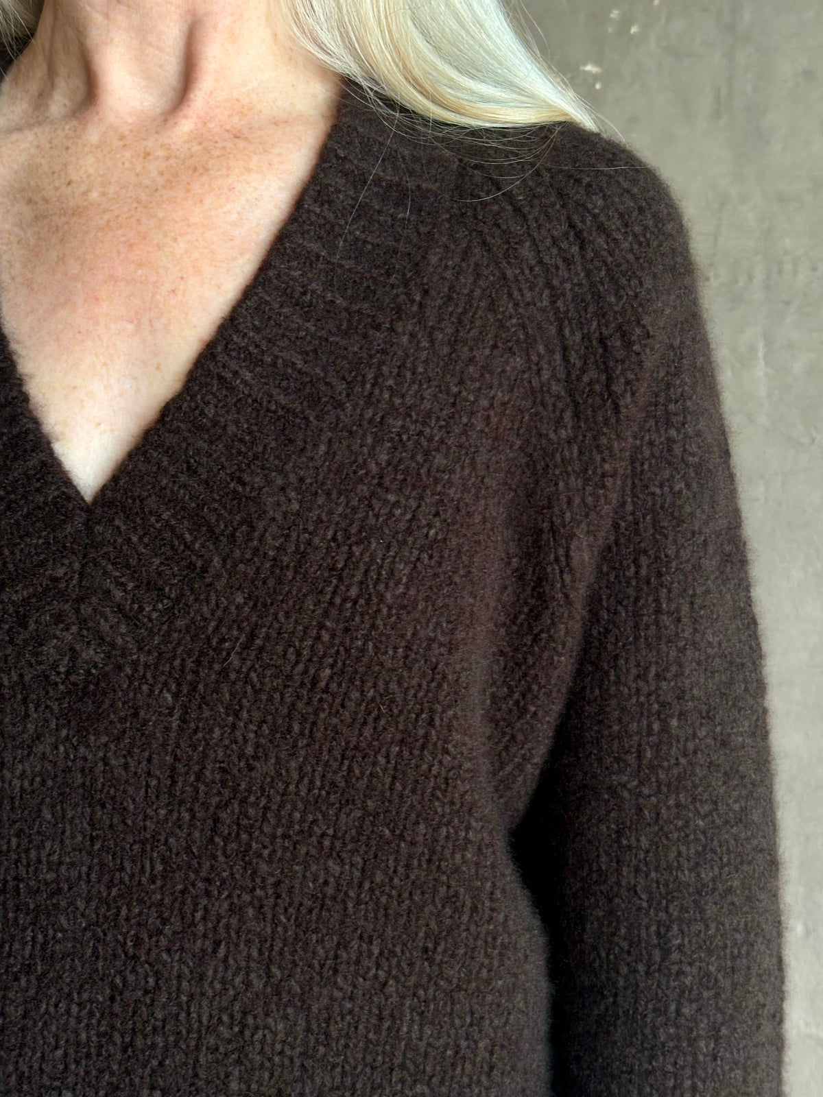 Mature woman wearing Nili Lotan's Isley Sweater Dark brown cashmere-silk  relaxed V-neck silhouette. Ultra-luxe
