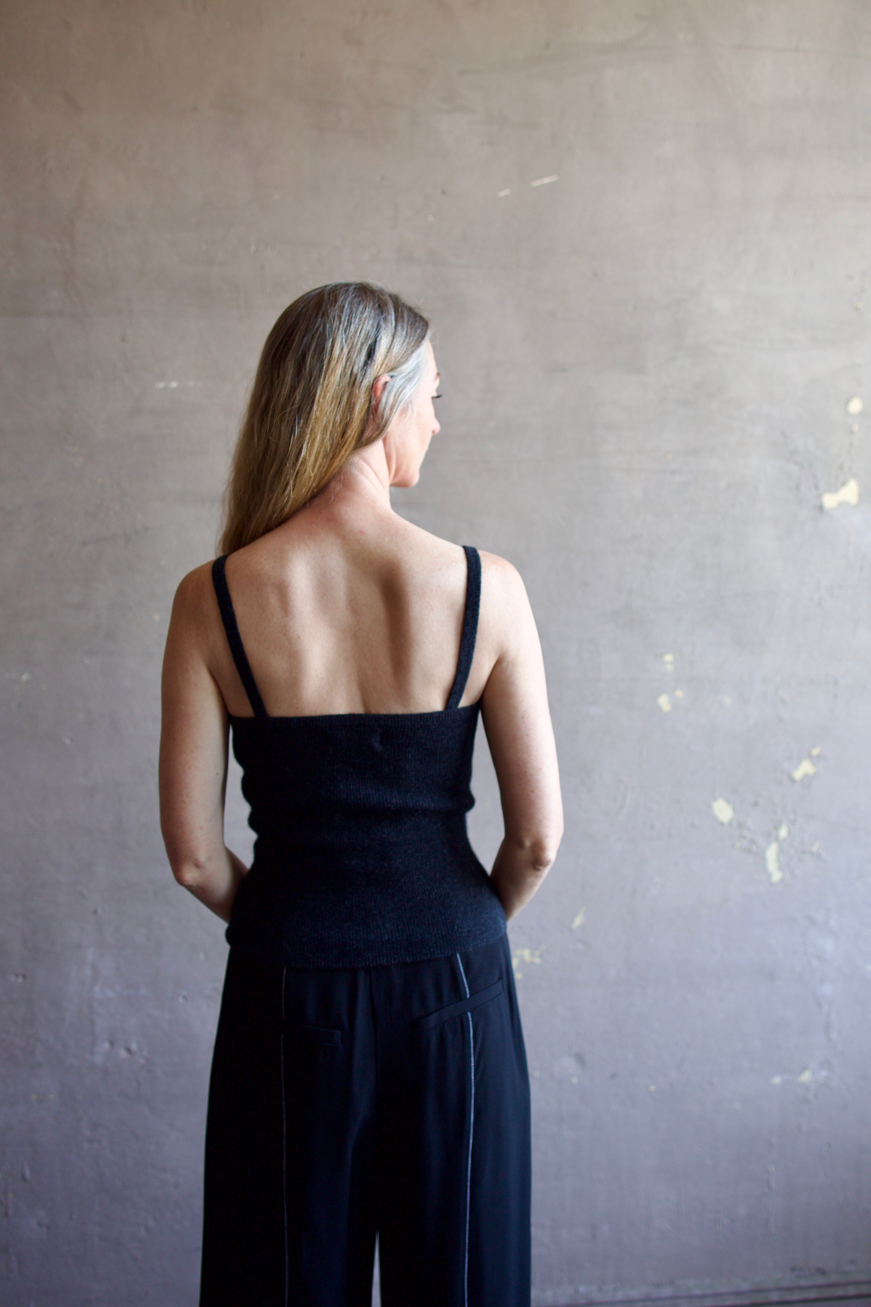 Image featuring a woman wearing the Ribbed Cami by Naadam with a v neckline, thin straps, and tailored fit in charcoal heather grey.