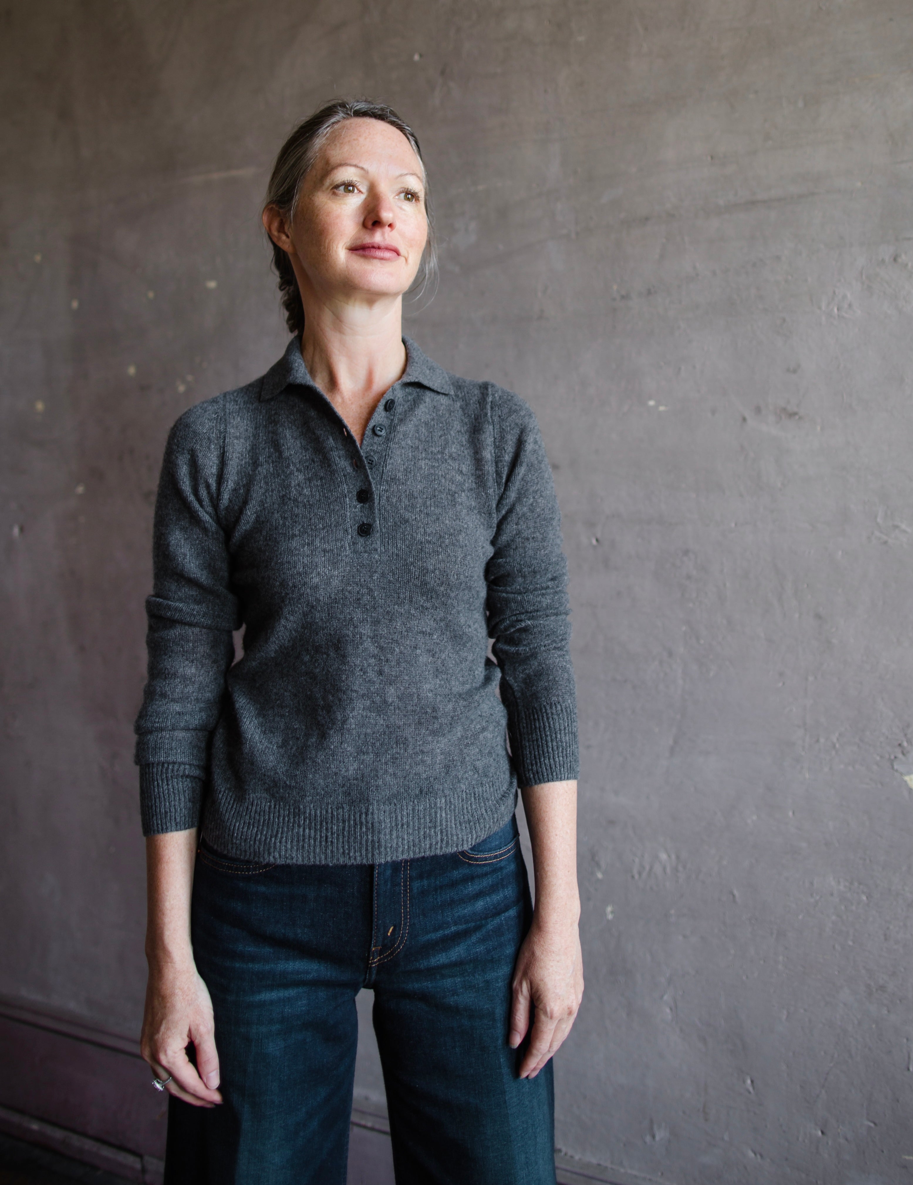 Image featuring a woman wearing the Naadam featherweight cashmere polo in dark grey