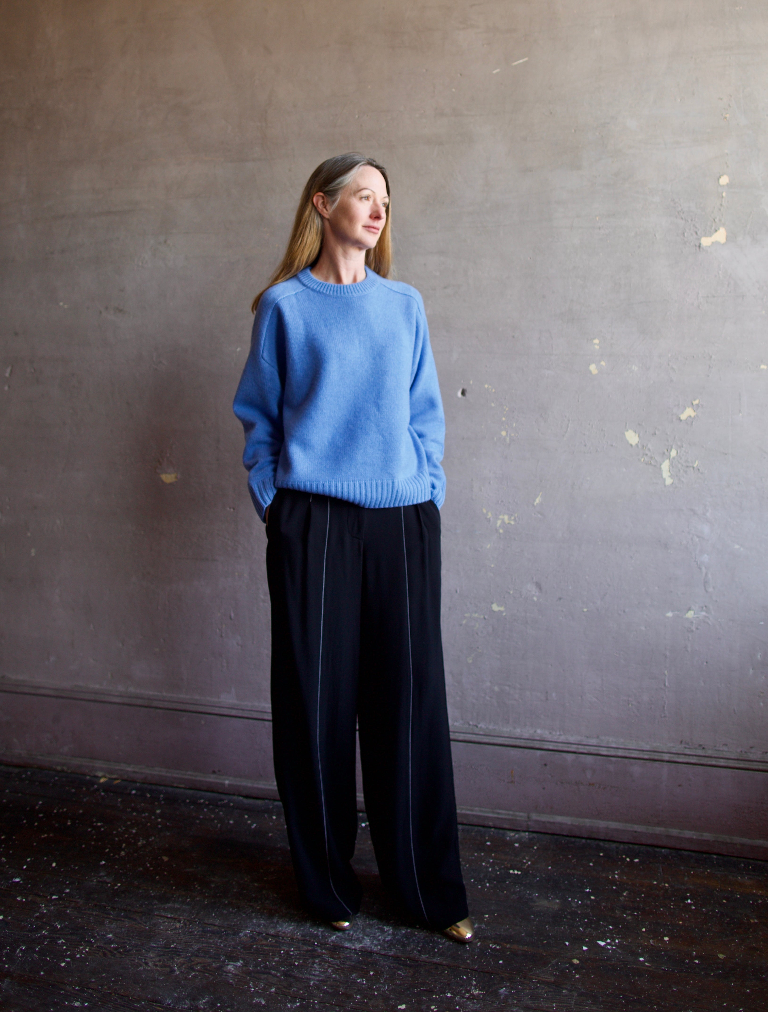 Image featuring a woman wearing the Super Luxe Cashmere Sweater by Naadam with a crew neck neckline, drop shoulder and a relaxed fit in bright blue.