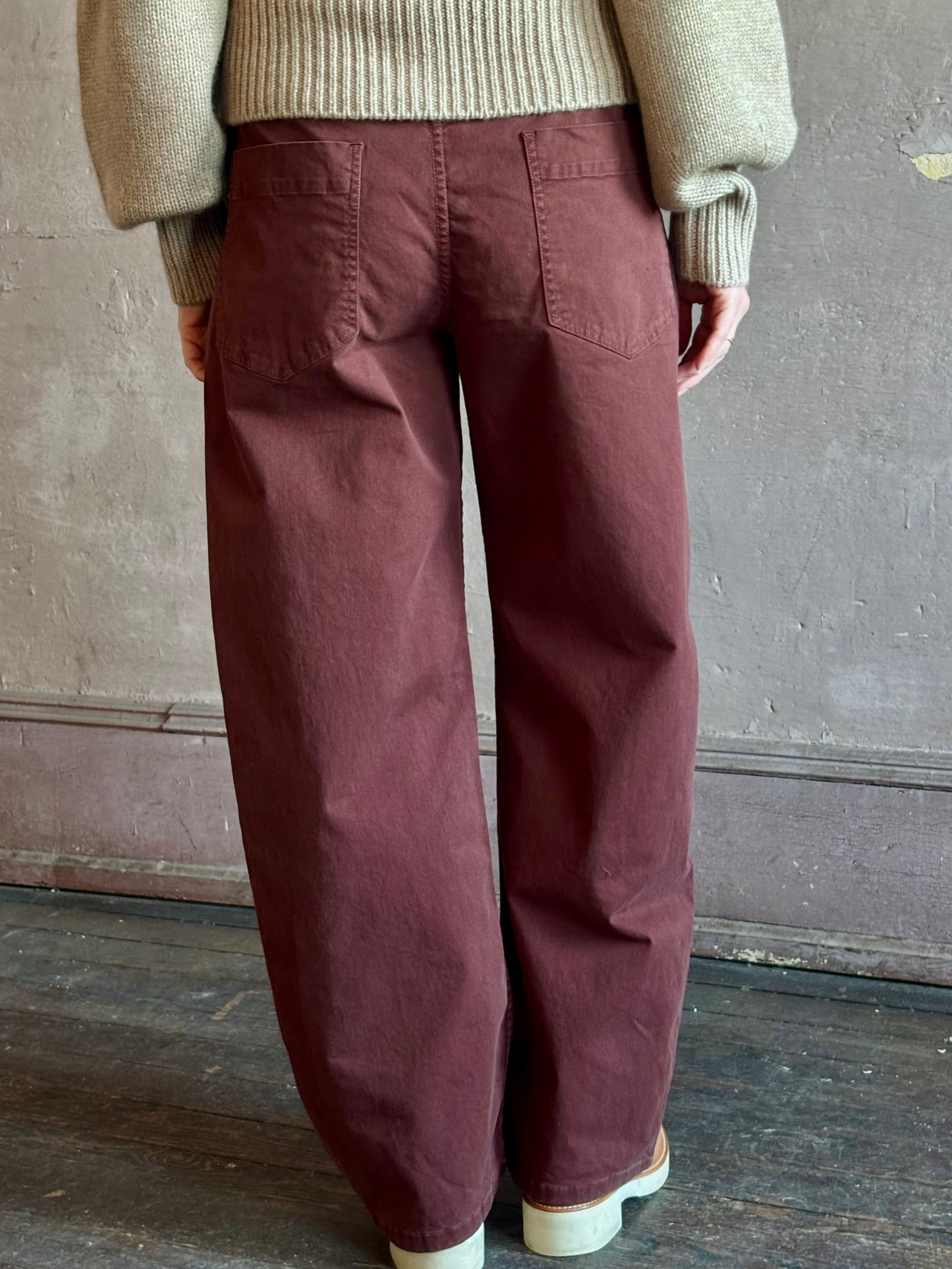 Back view of woman wearing Nili Lotan’s Tribeca Pant in a cotton-elastane barrel leg  relaxed fit back patch pockets in burgundy Made in the USA