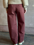 Back view of woman wearing Nili Lotan’s Tribeca Pant in a cotton-elastane barrel leg  relaxed fit back patch pockets in burgundy Made in the USA