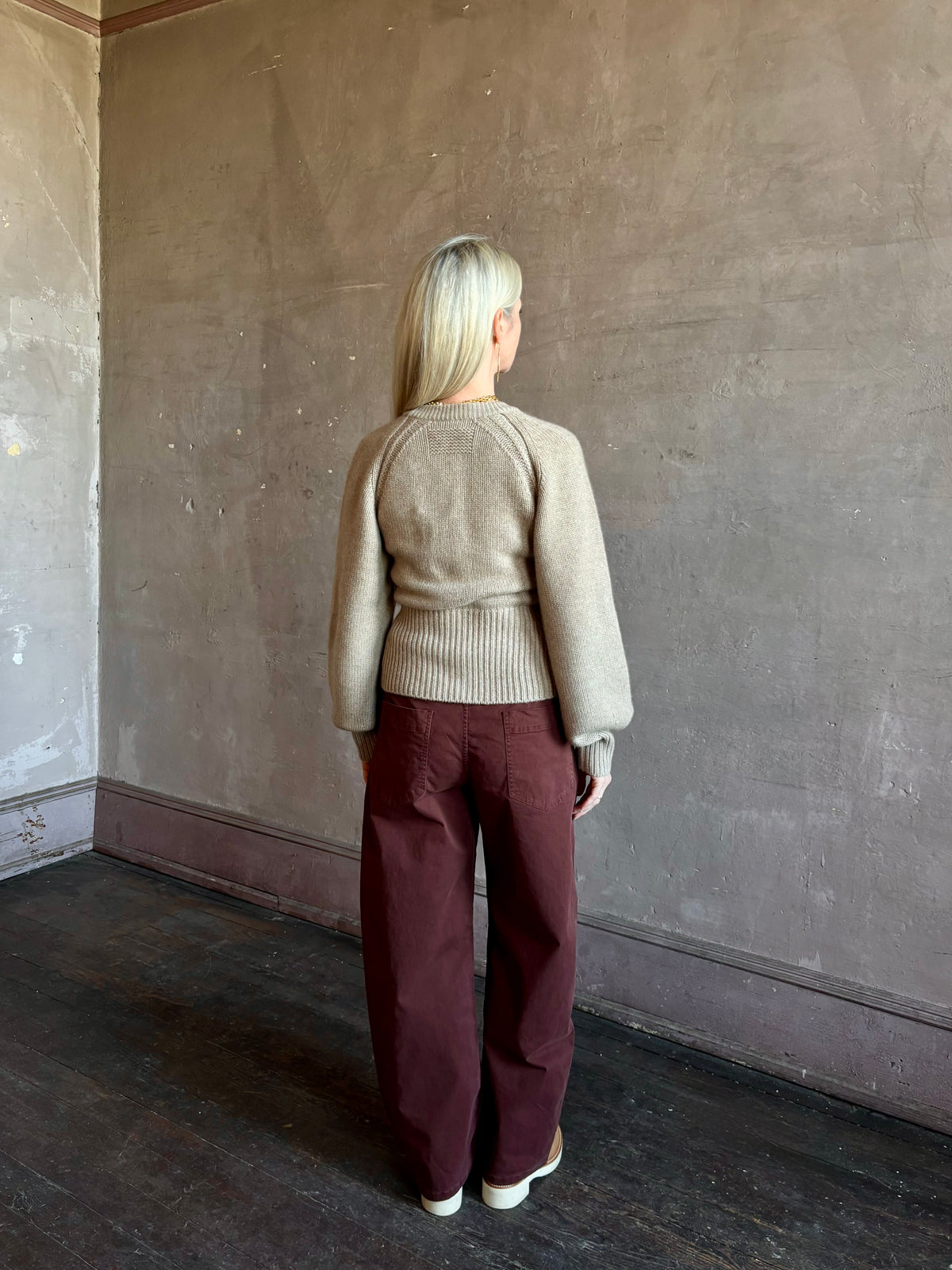 Mature woman wearing Nili Lotan’s Tribeca Pant in Cabernet a cotton-elastane barrel leg with a relaxed fit mid-rise jewel-toned, effortlessly easy