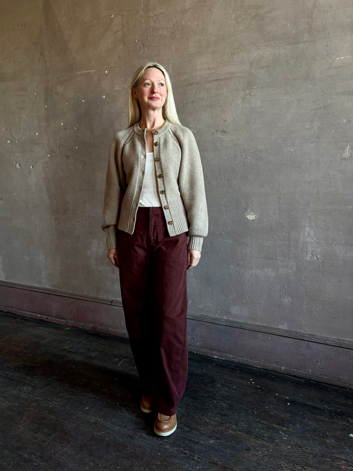 Mature woman wearing Nili Lotan Tribeca Pant in Cabernet with mid-rise cotton-elastane barrel leg bar-and-zip closure easy fit Made in the USA