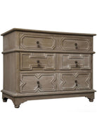 A traditional wooden dresser with three drawers, featuring metal pulls and hand-carved geometric patterns, with a weathered finish.