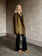 Image of woman wearing luxury brand Proenza Schoulder double faced green wool coat with detachable collar and front pockets