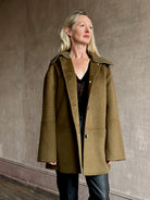 Image of woman wearing luxury brand Proenza Schoulder double faced green wool coat with detachable collar and front pockets