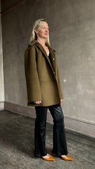 Image of woman wearing luxury brand Proenza Schoulder double faced green wool coat with detachable collar and classic back detailing