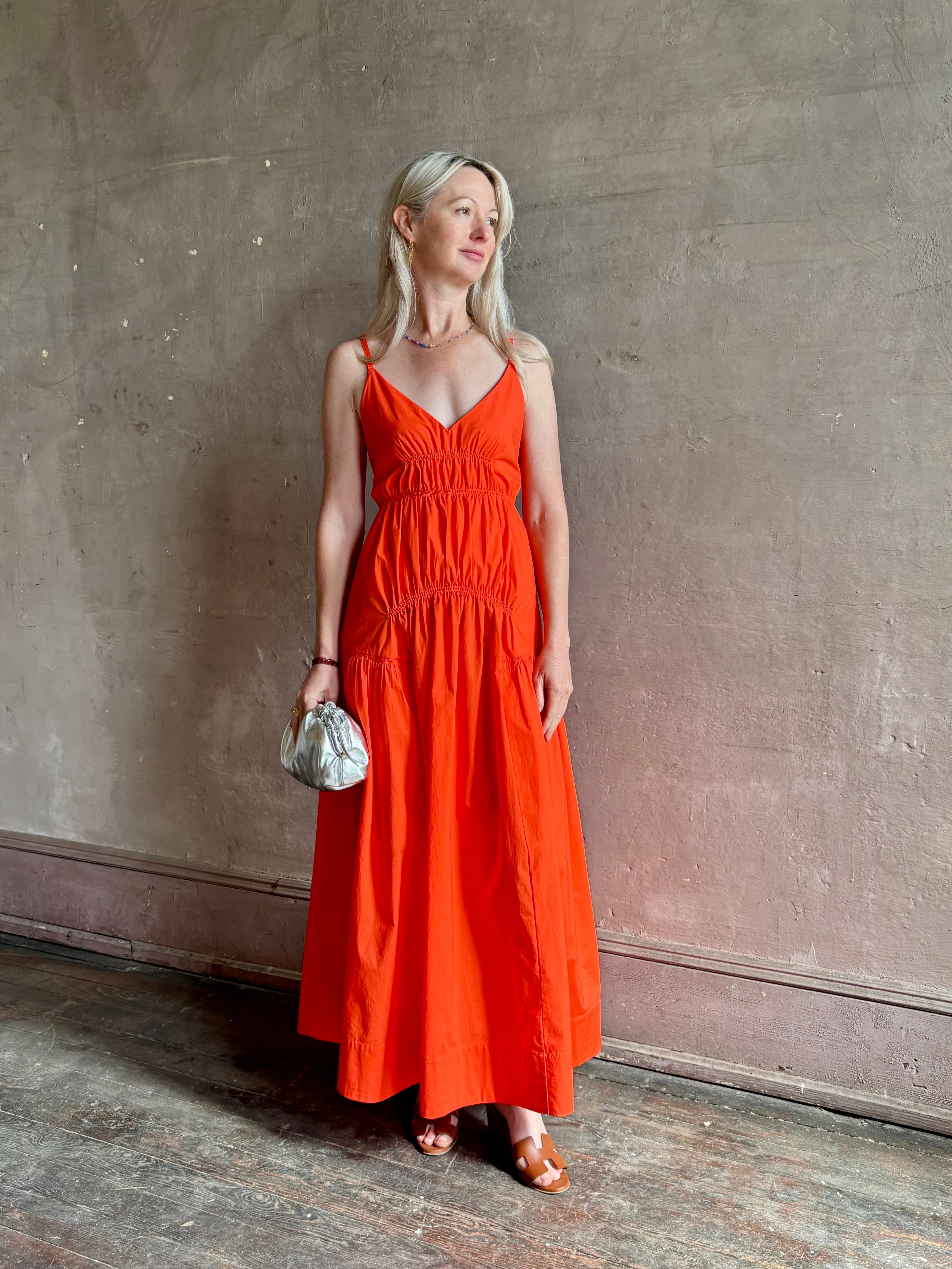 Mature woman wearing  Michelyn maxi designer Dress from Proenza Schouler rendered in a striking orange and crafted from a refined cotton blend with adjustable spaghetti straps, v-neck, pockets, hidden zipper closure and modern ruching details