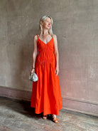 Mature woman wearing  Michelyn maxi designer Dress from Proenza Schouler rendered in a striking orange and crafted from a refined cotton blend with adjustable spaghetti straps, v-neck, pockets, hidden zipper closure and modern ruching details