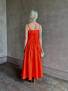 Mature woman wearing  Michelyn maxi designer Dress from Proenza Schouler rendered in a striking orange and crafted from a refined cotton blend with adjustable spaghetti straps, v-neck, pockets, hidden zipper closure and modern ruching details
