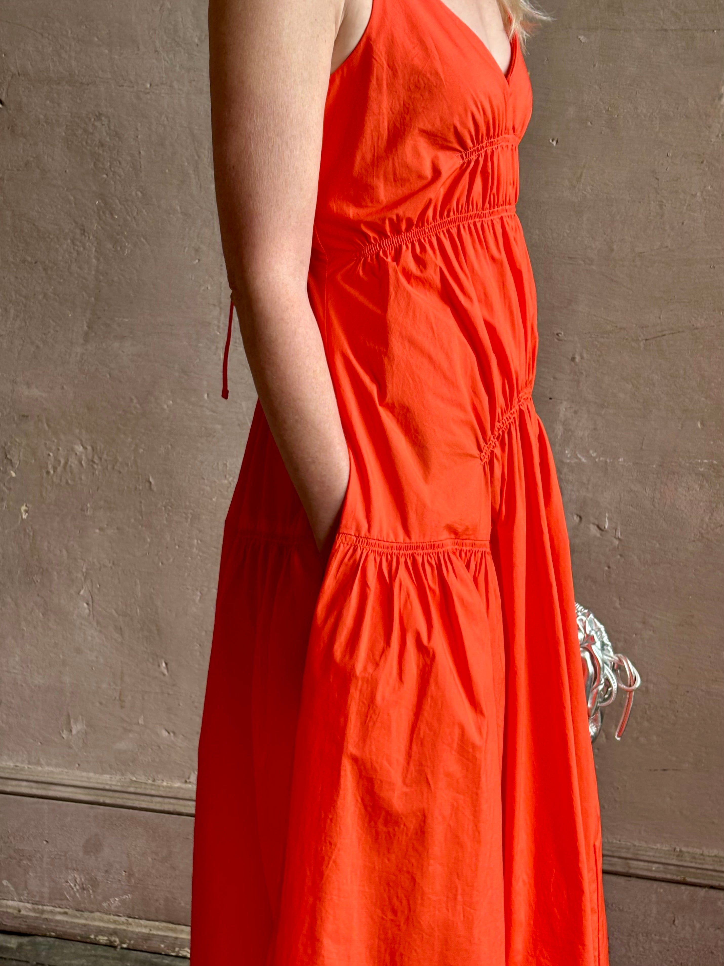 Mature woman wearing  Michelyn maxi designer Dress from Proenza Schouler rendered in a striking orange and crafted from a refined cotton blend with adjustable spaghetti straps, v-neck, pockets, hidden zipper closure and modern ruching details