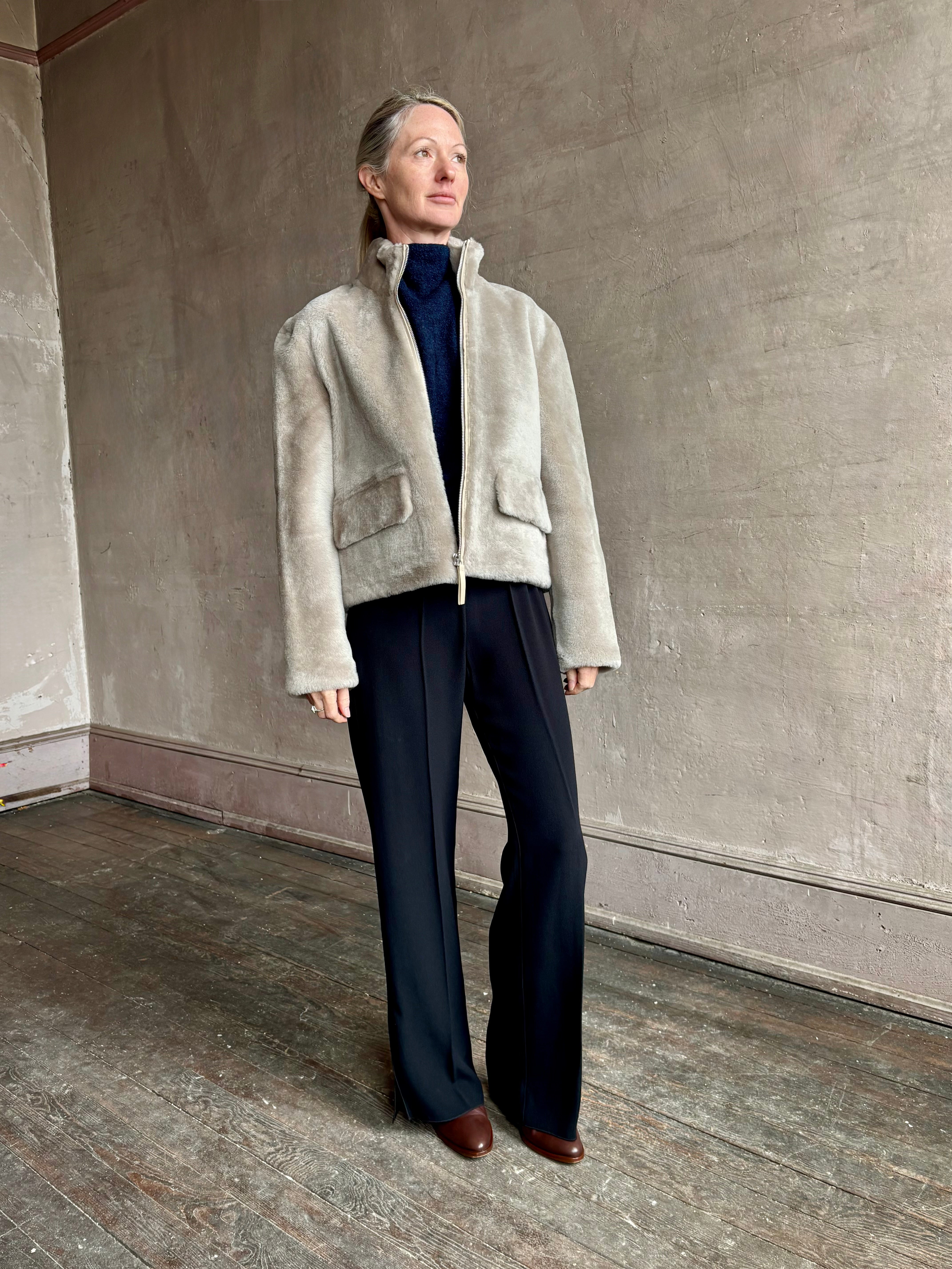 Image of a mature woman wearing Proenza Schouler Scarlett shearling jacket with a zip front and pockets for  the ultimate warm luxury coat in a neutral