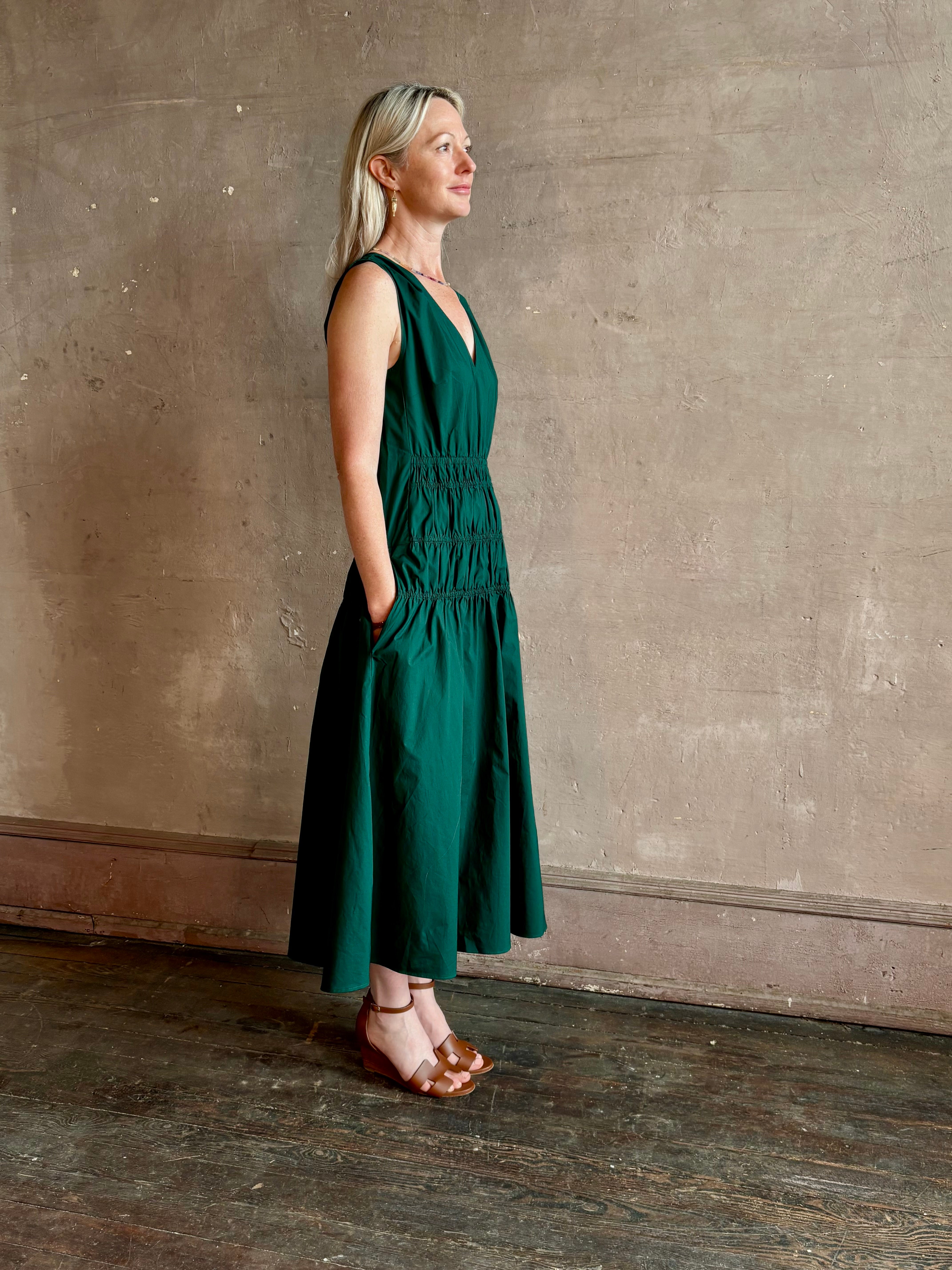 Mature woman wearing Loren Dress from Proenza Schouler White Lable rendered in aspruce green and crafted from a cotton elastane blend with v-neck, sleeveless, pockets, and rushed waist