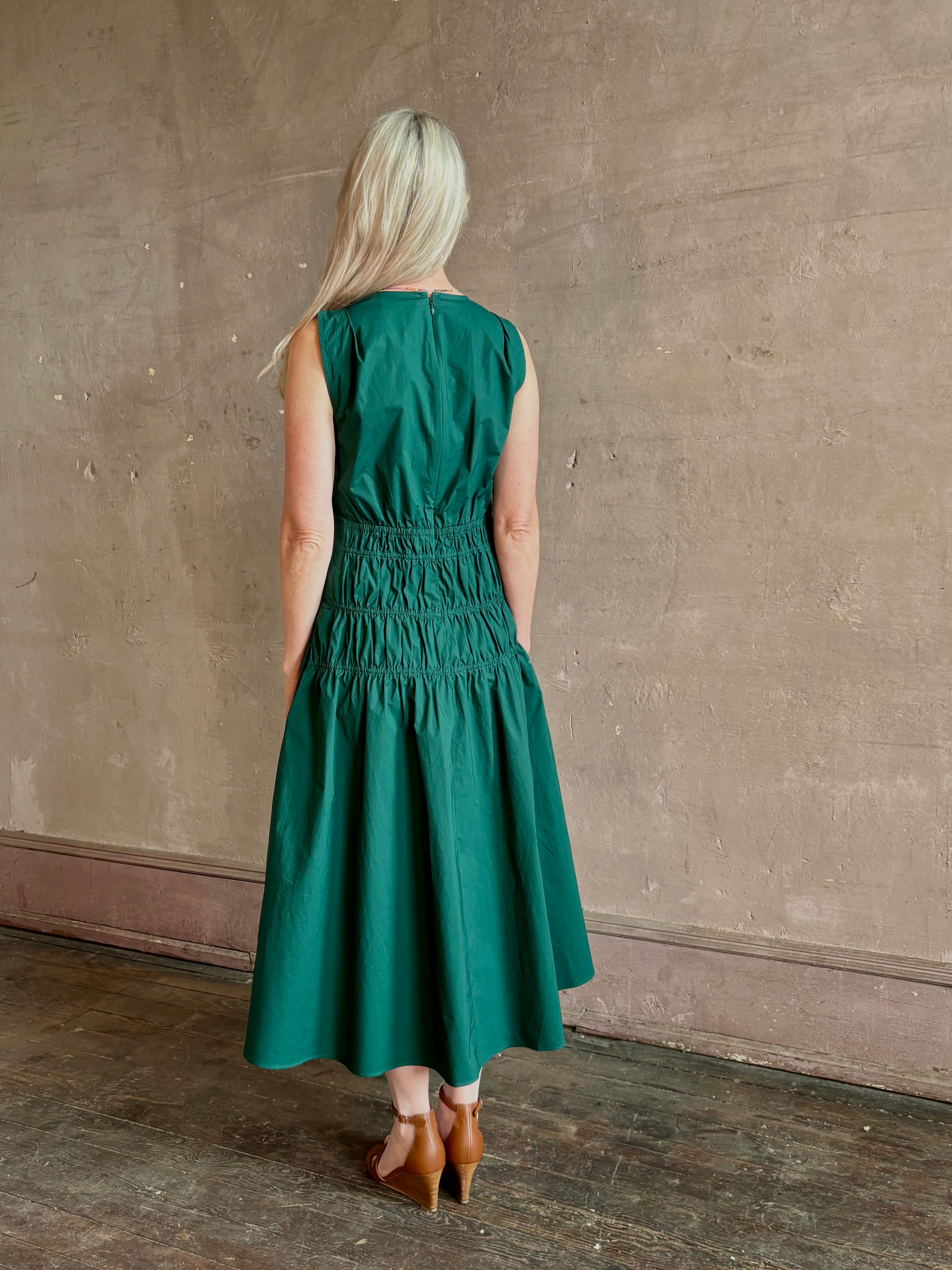 Mature woman wearing Loren Dress from Proenza Schouler White Lable rendered in aspruce green and crafted from a cotton elastane blend with v-neck, sleeveless, pockets, and rushed waist