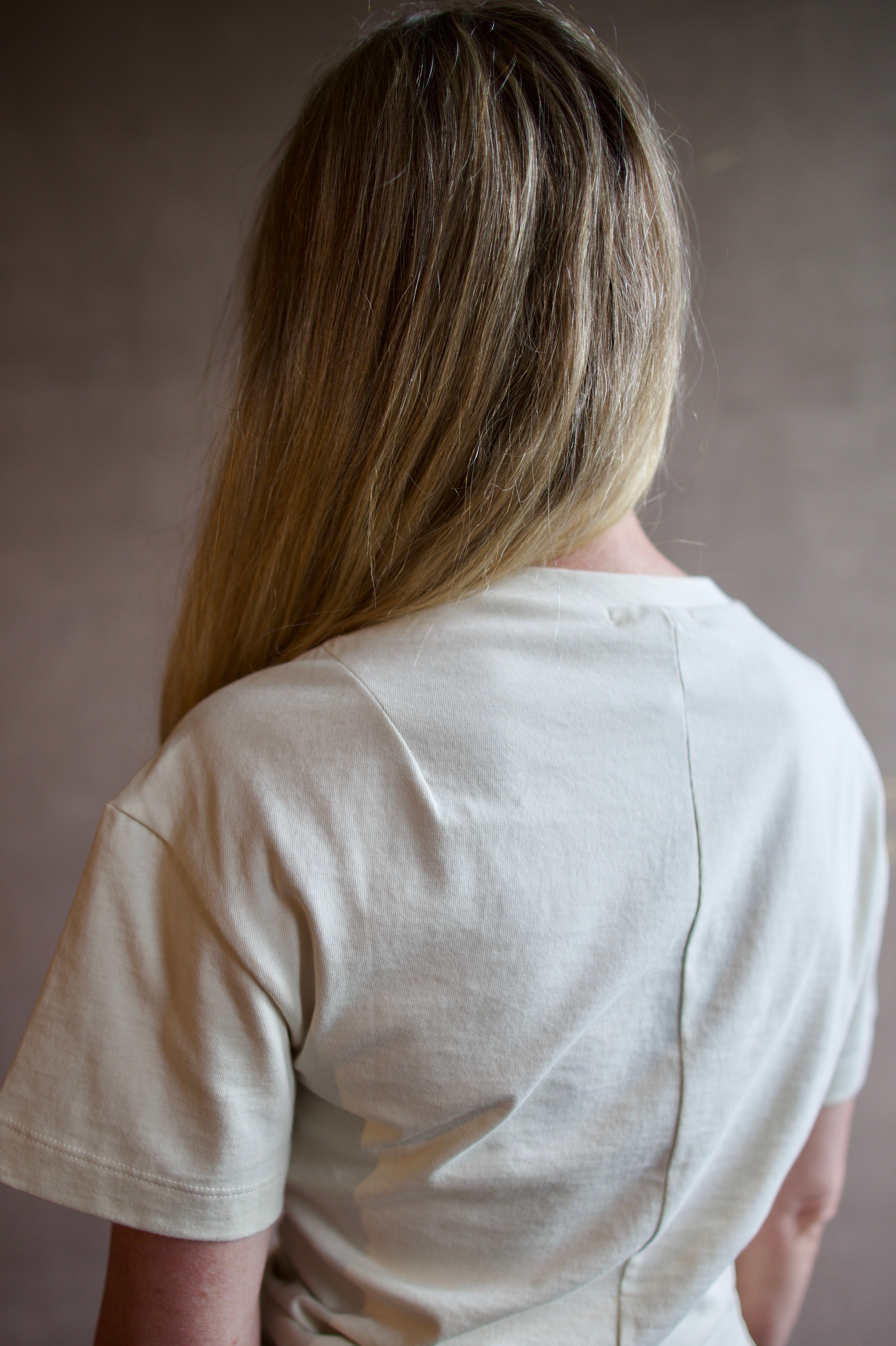 Image of model wearing designer Rag and Bone Mica ivory Tee shirt with contemporary twist waist design in premium cotton fabric
