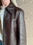 Close up image of mature woman wearing Proenza Schouler White Label Annabel Leather Jacket in Chocolate Brown with intricate seam details on front of jacket that wrap around the back