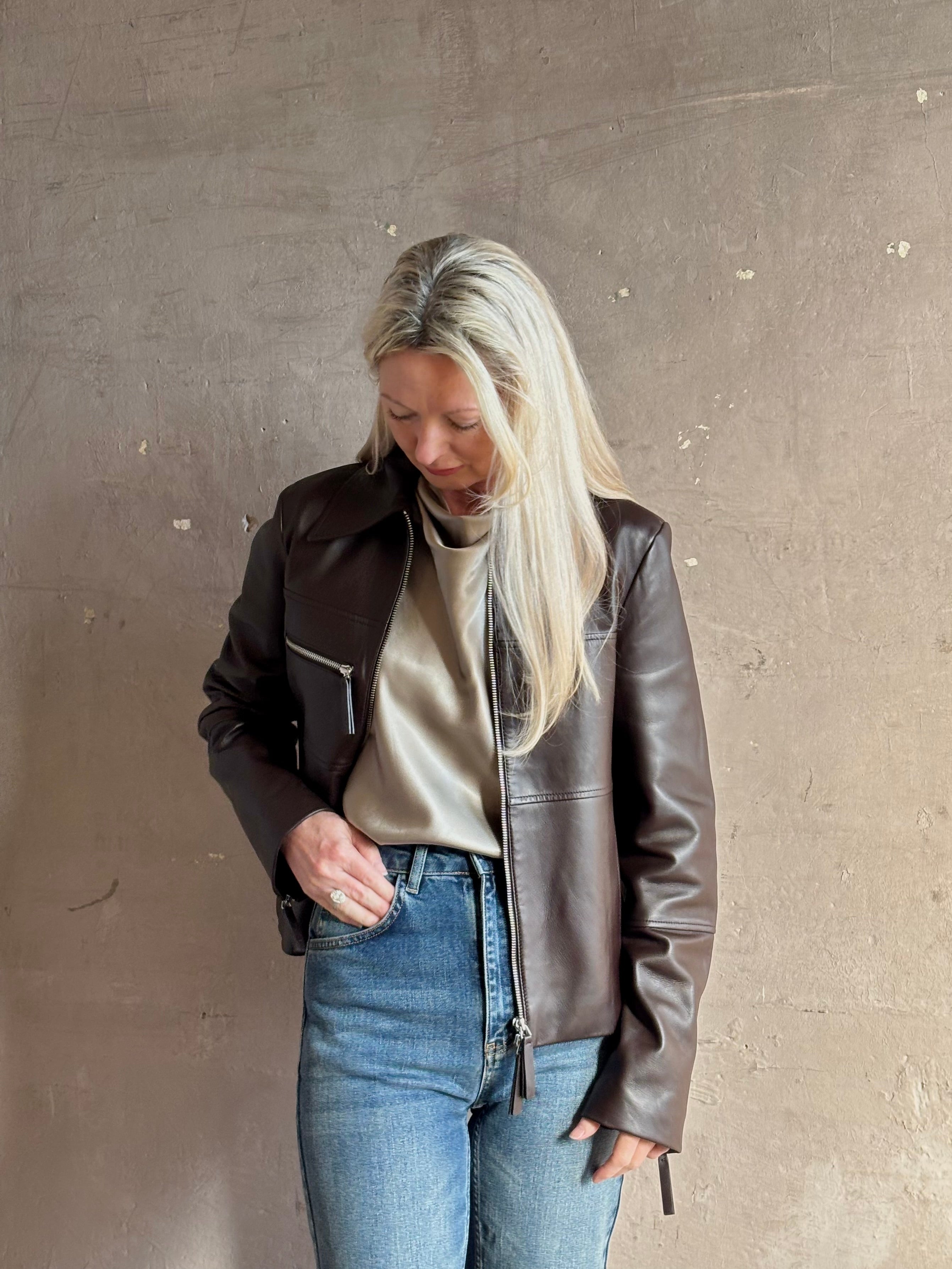 Mature woman wearing Proenza Schouler White Label Annabel lambskin Leather biker Jacket in Chocolate Brown with two way front zipper and straight hem